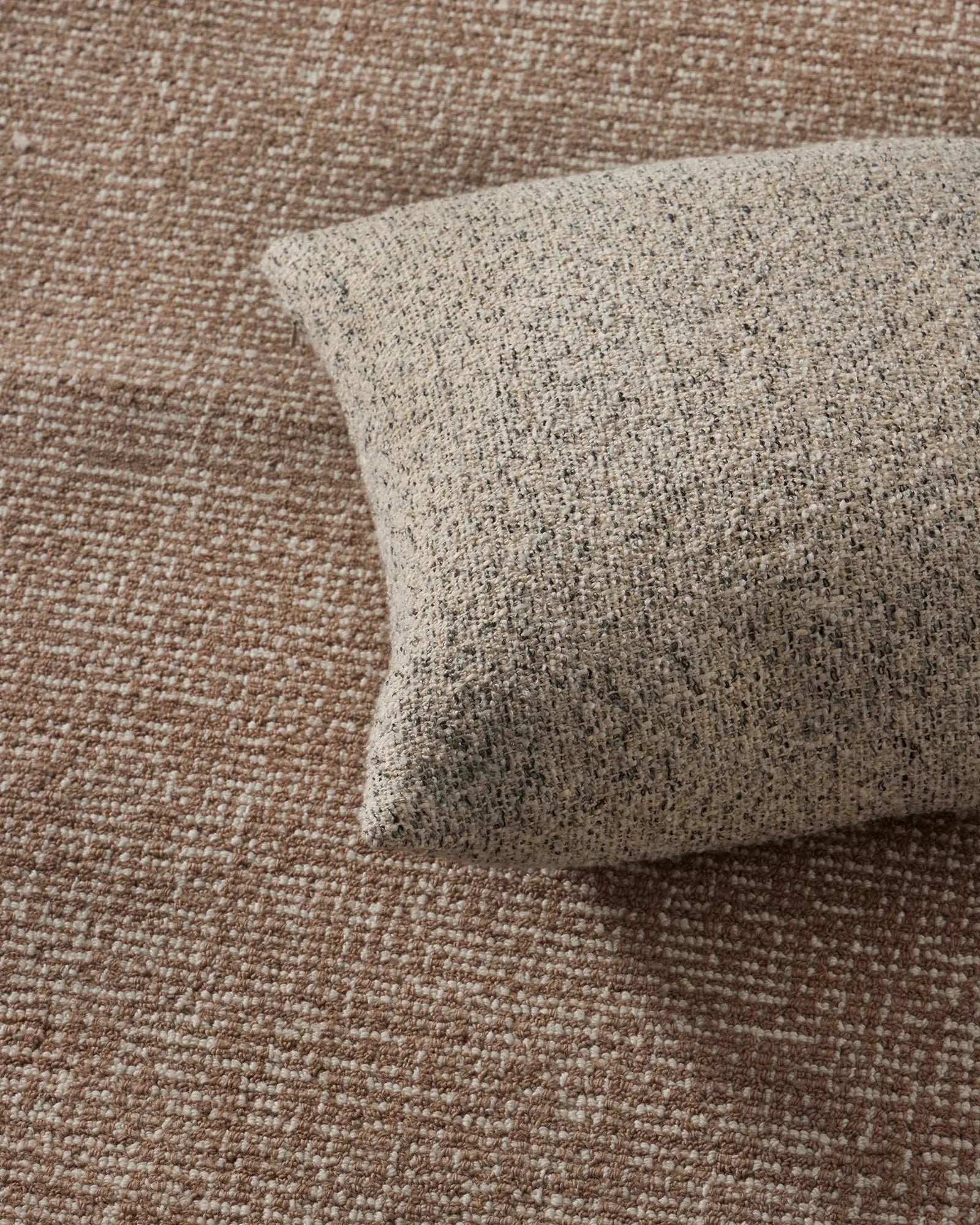 Neutral textured cushion layered on warm mocha linen, showcasing tactile woven fabrics and earthy tonal palette in relaxed minimalist home styling