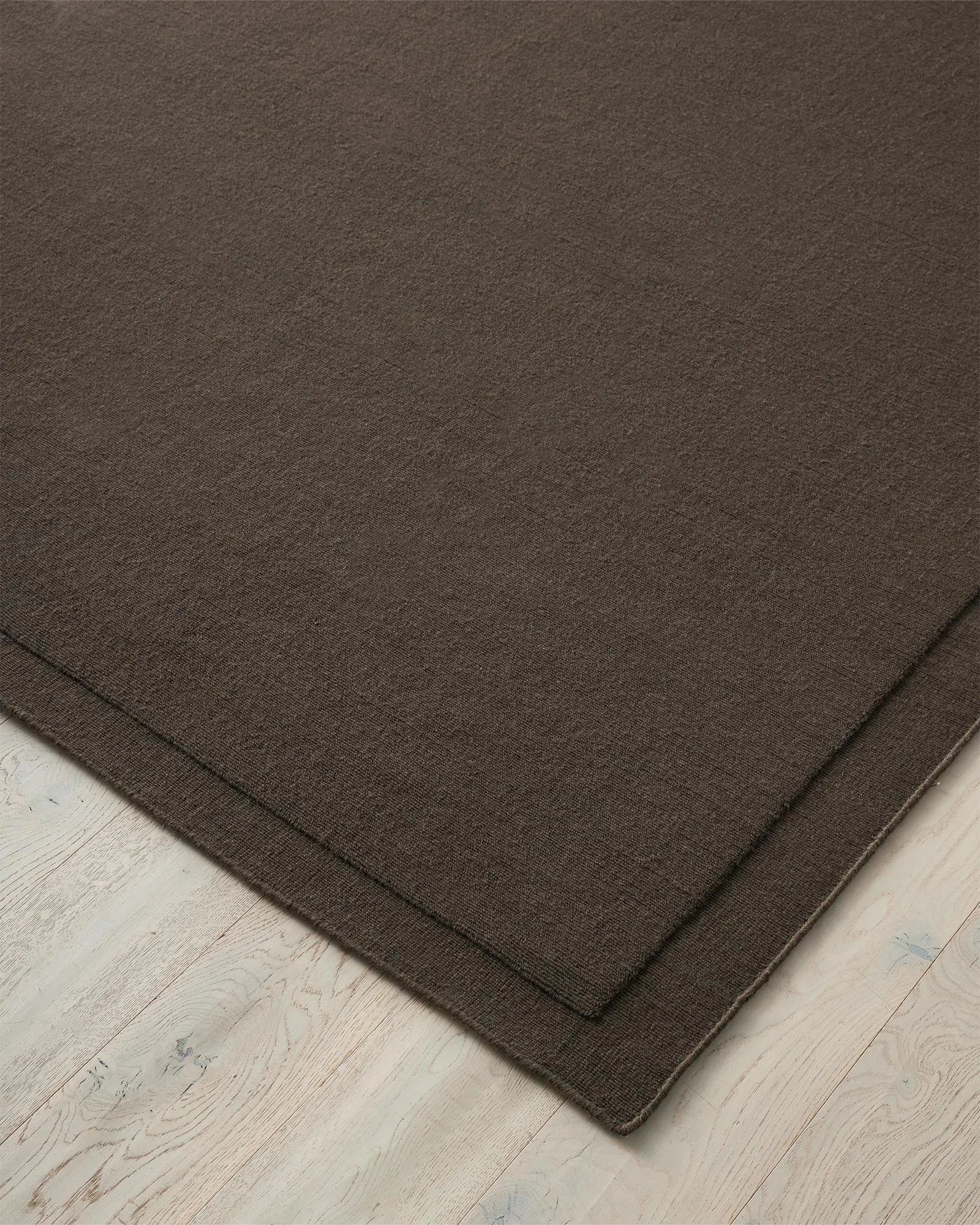 Cassio Fudge rug in dark mocha, close-up of woven loop pile texture with serged edge detail, by Weave Home