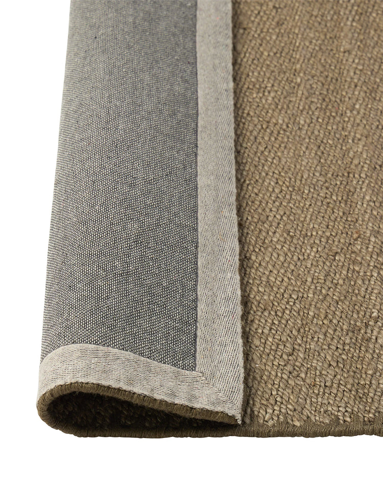 Monroe Flint rug detail showing soft green-grey weave with tonal blanket stitch border, by Weave Home
