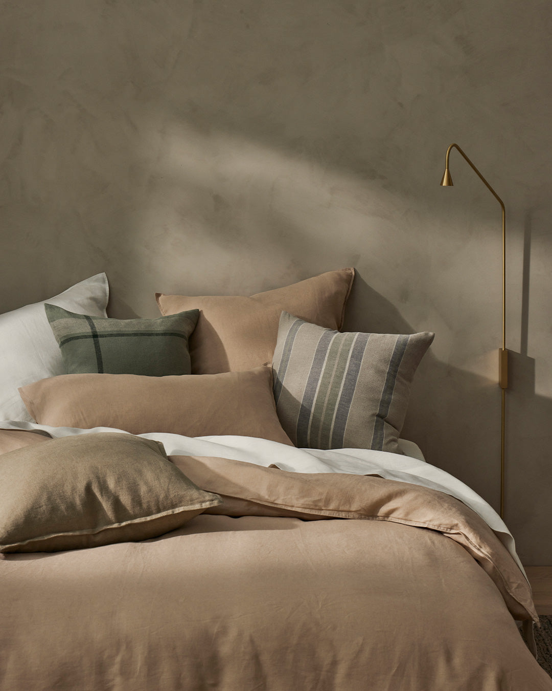 Ravello Flat Sheet in Shell, European linen, layered with striped cushions in sage and taupe on bed by Weave Home