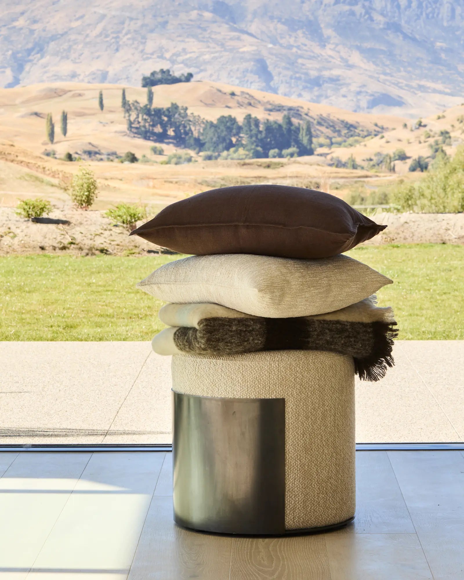 Como Cocoa linen cushion in warm chocolate brown, stacked with neutral tones, showcasing stone-washed matte texture by Weave Home