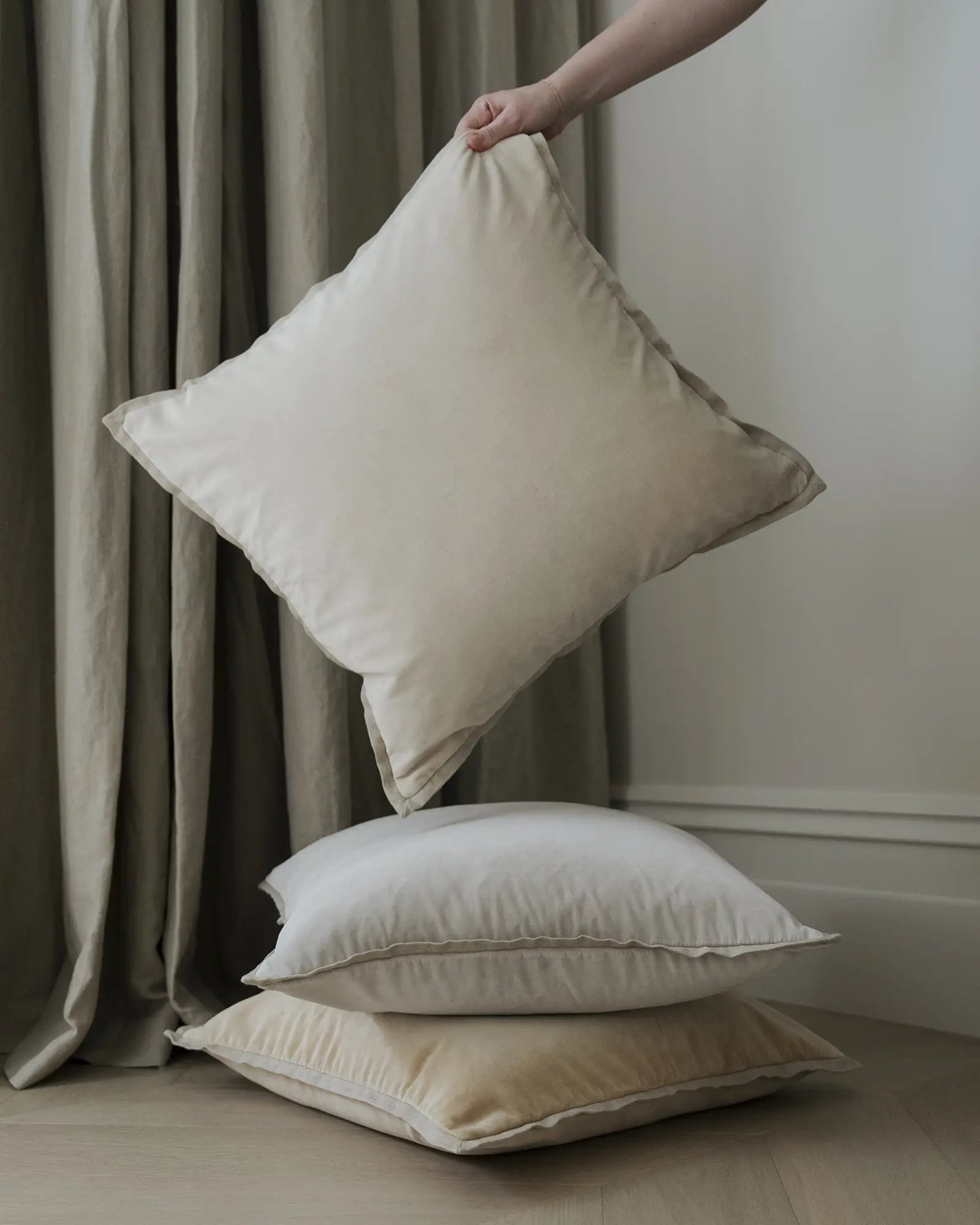 Neutral minimalist cushion styling with stacked Francesca pillows in cream and natural tones, earthy curtain backdrop, soft textures and clean aesthetic