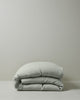 Ravello Quilt Cover in Sage, European linen rolled in soft folded layers against neutral background by Weave Home