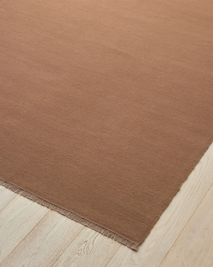 Jacqueline Rosewood wool rug, flat-weave high-traffic rug in dusty rose with warm brown undertones, fringe detail visible, by Weave Home