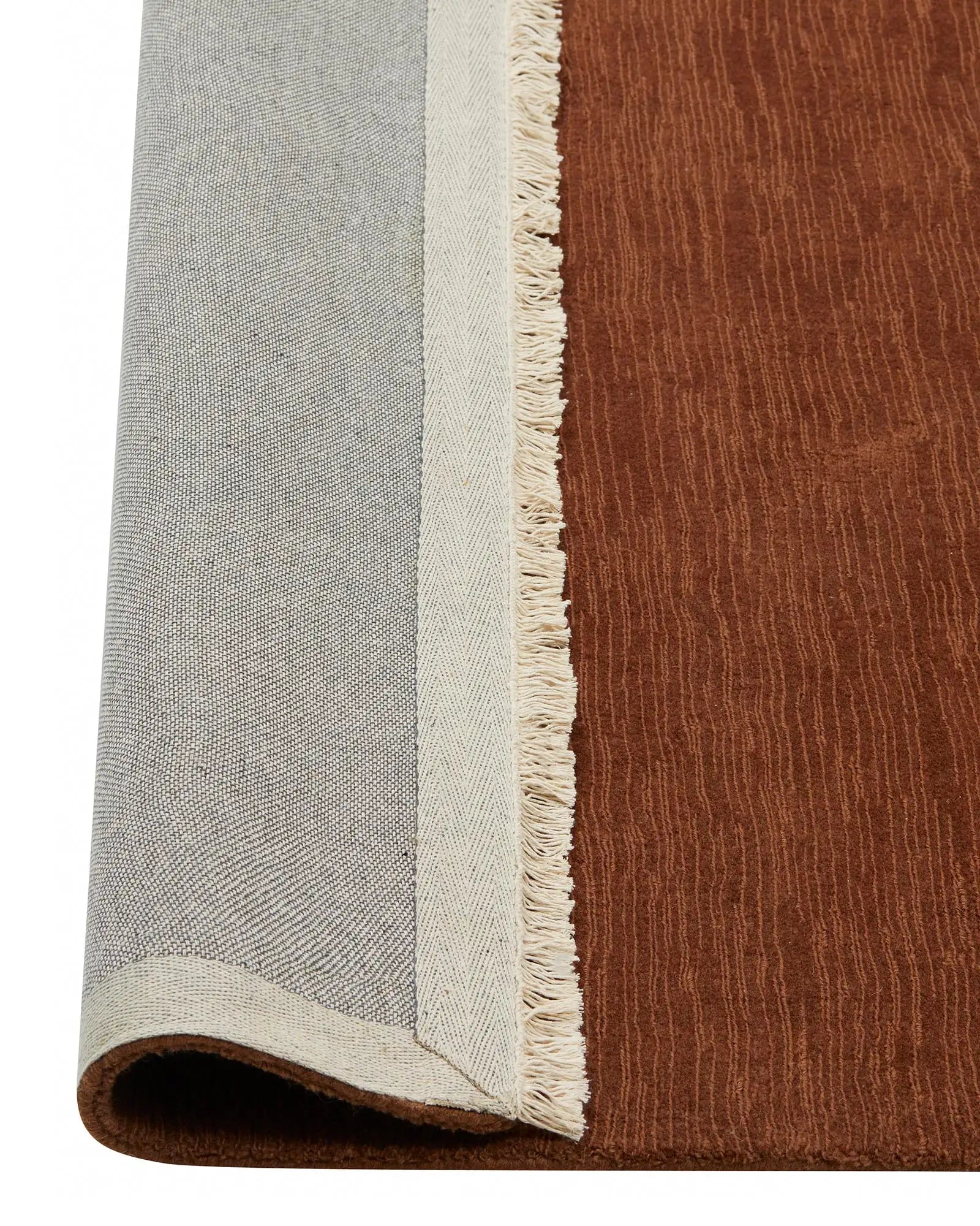 Alessandre Clay low-traffic rug in warm red-brown wool with cream fringe edge and cotton backing, detail view by Weave Home
