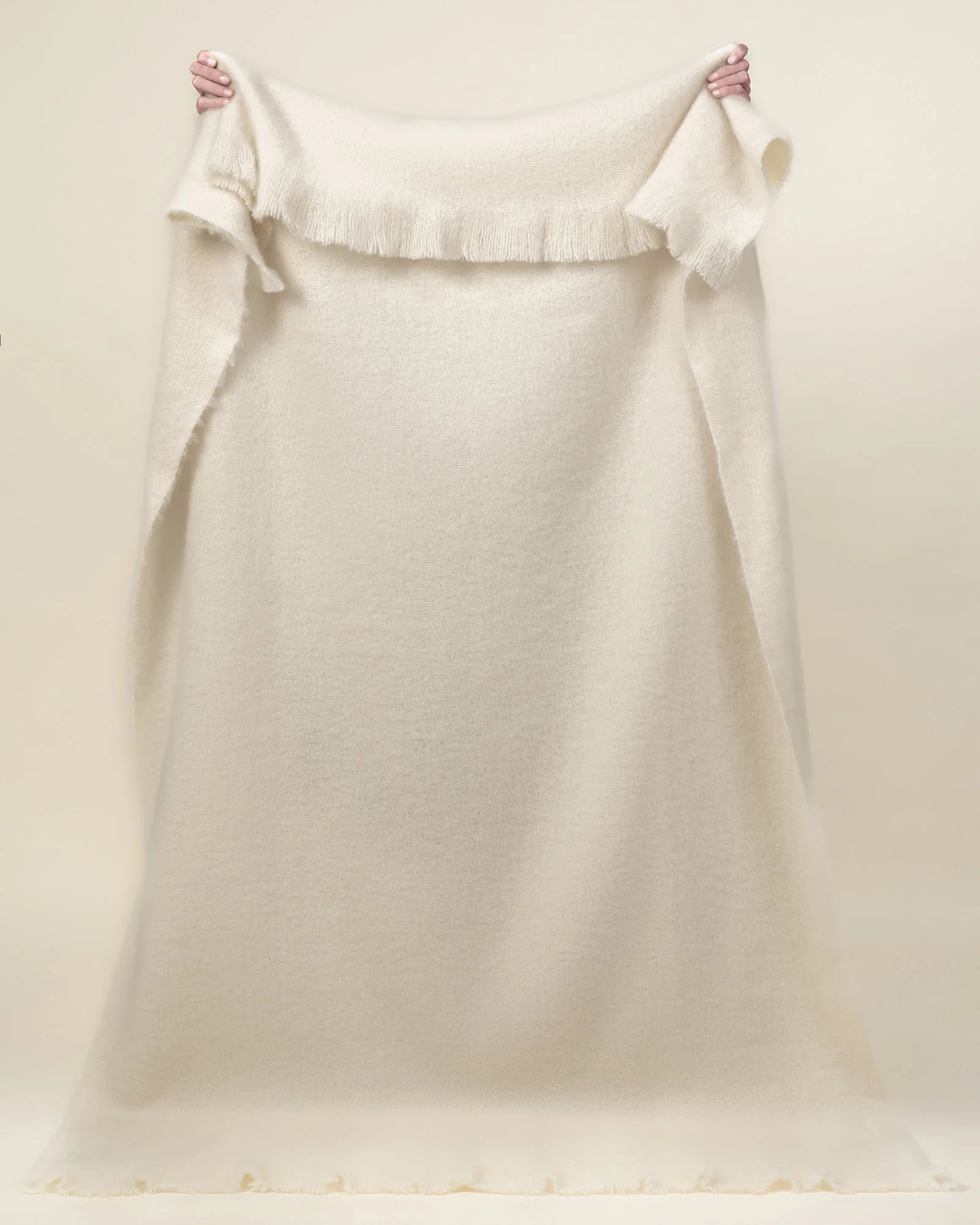 Hyde Cream wool blend throw held up to show fringe border detail, soft woven texture and voluminous weave by Weave Home