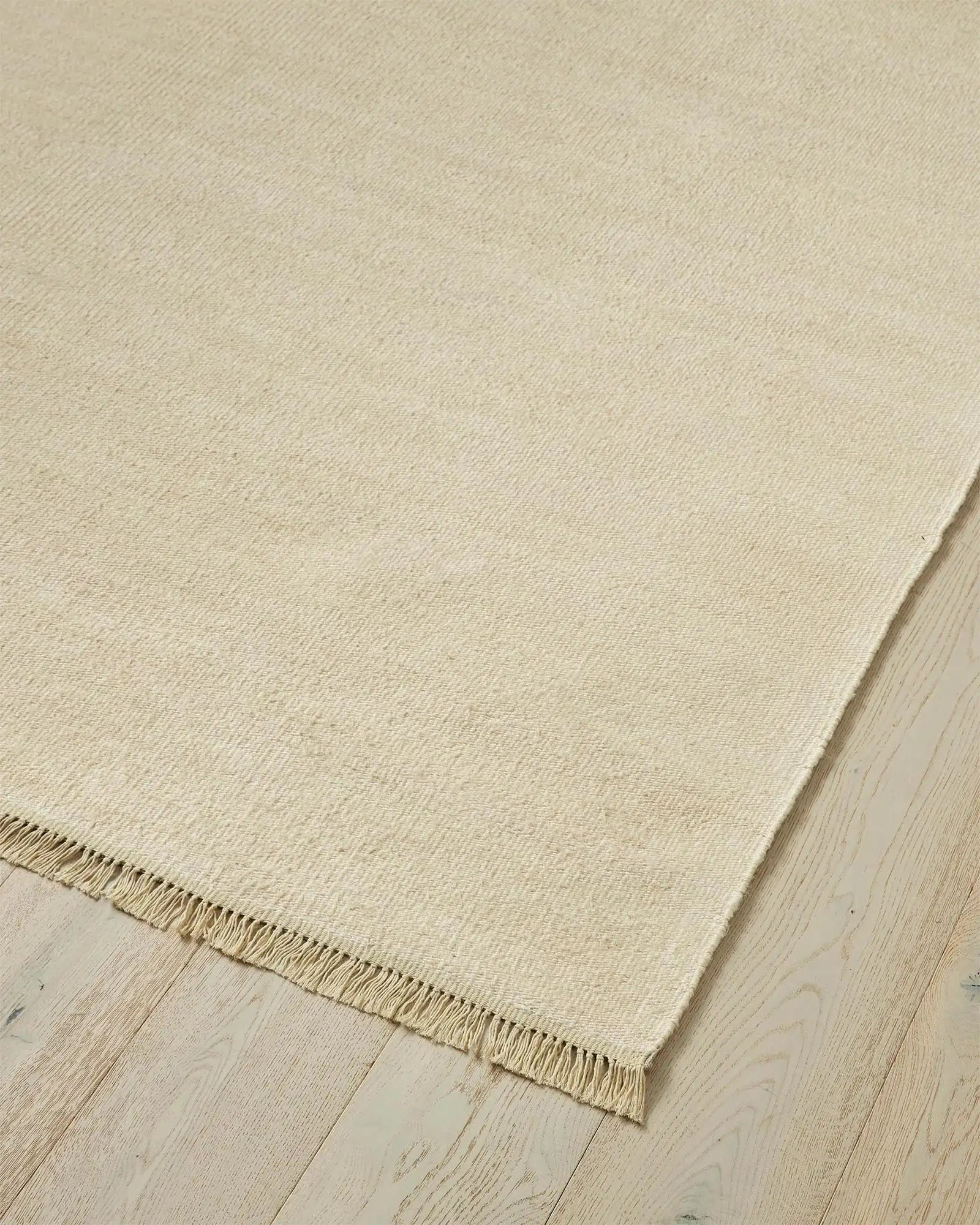 Emilio Canvas linen rug in light beige, corner detail showing fringe edge and flat-weave texture by Weave Home