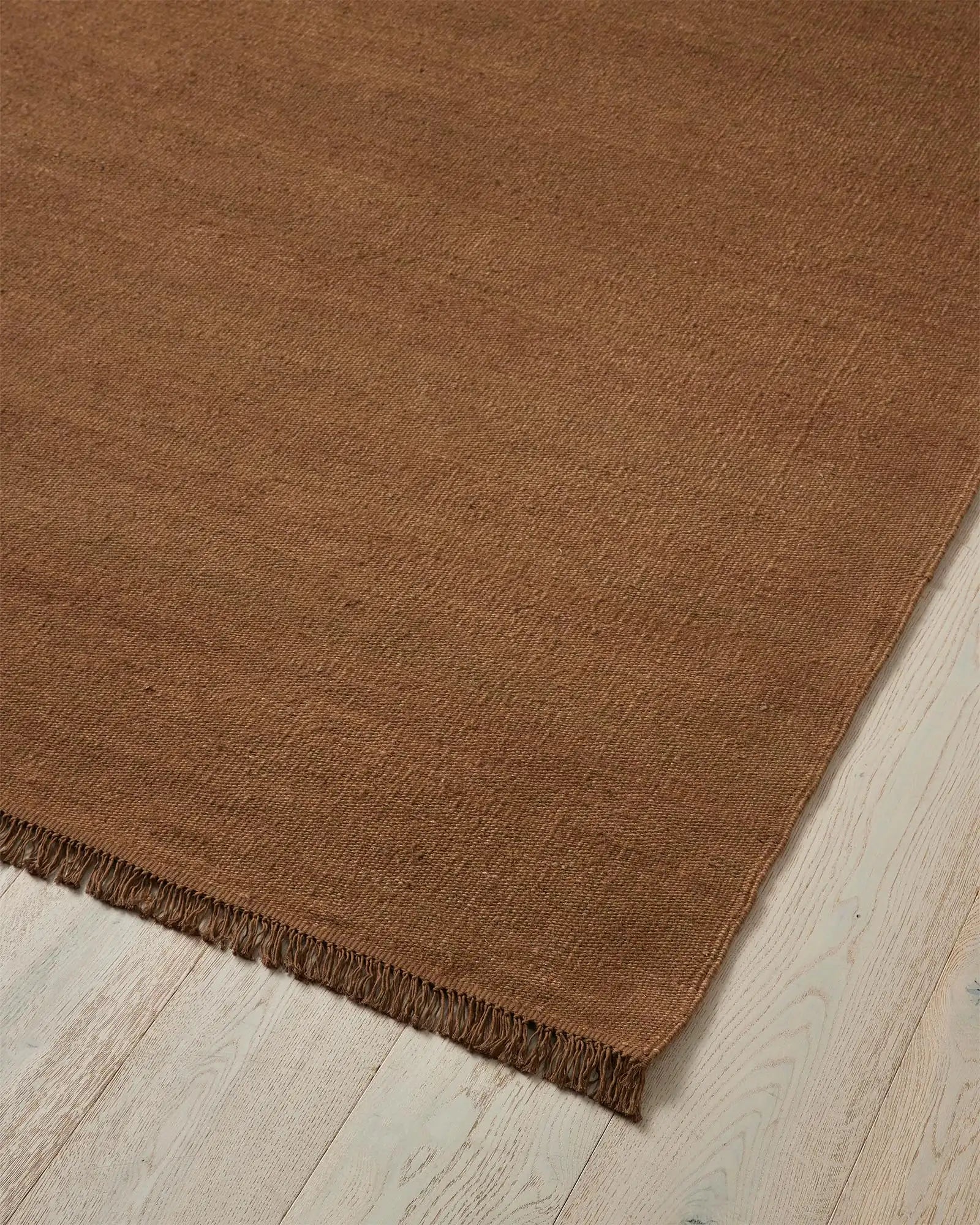 Emilio Toffee 2m x 3m linen rug, corner detail showing warm golden-brown flat-weave with fringe border by Weave Home