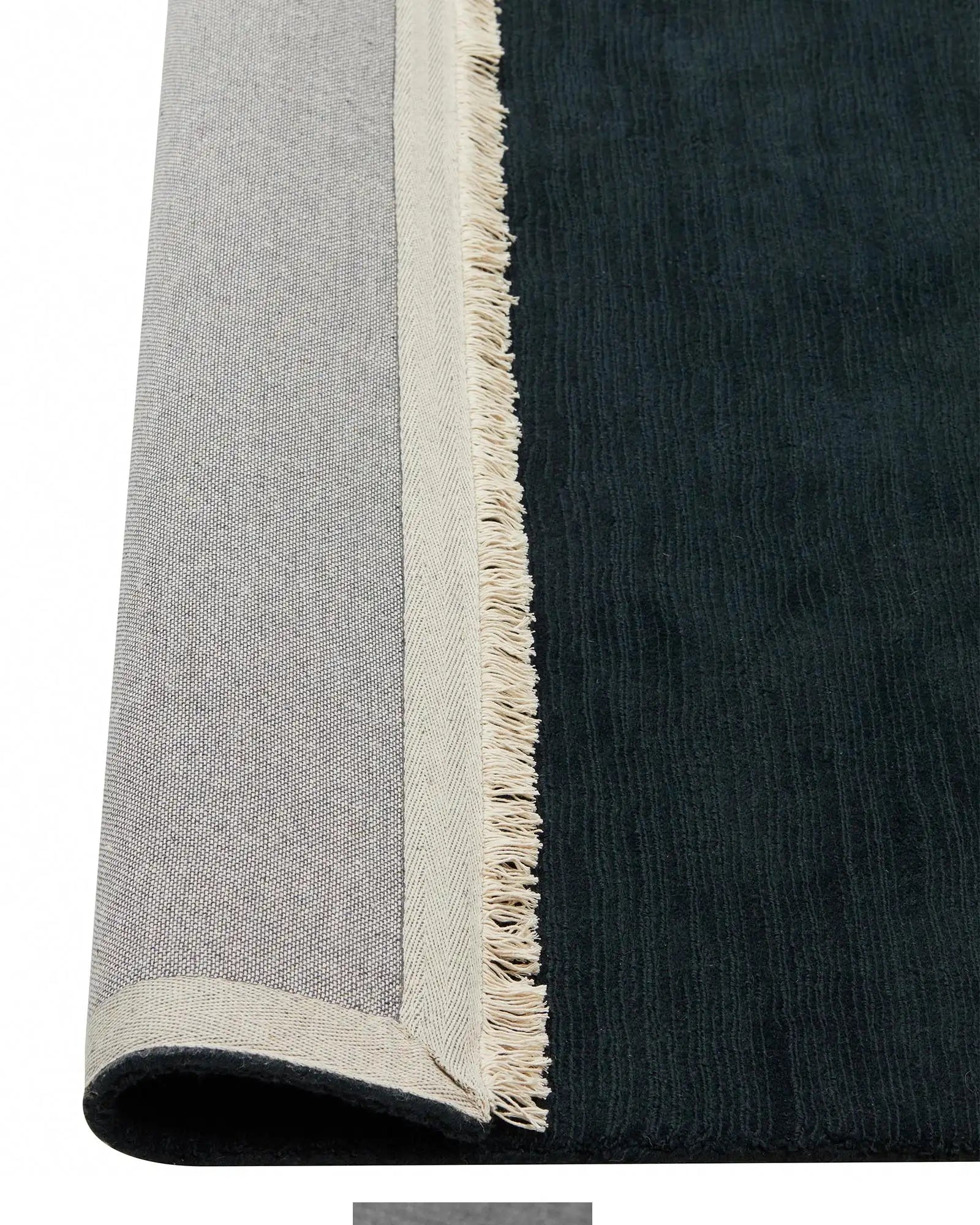 Alessandre Dusk rug detail showing charcoal wool with natural fringe edge and cotton backing by Weave Home