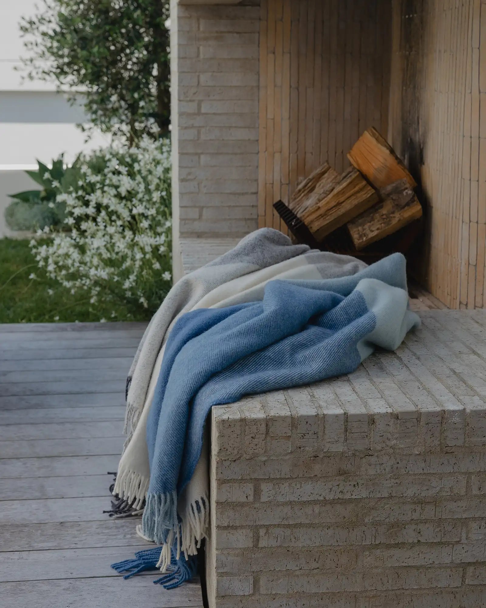 Bayswater Breeze throw in blue and white NZ wool with fringe edge, draped on brick wall by Weave Home