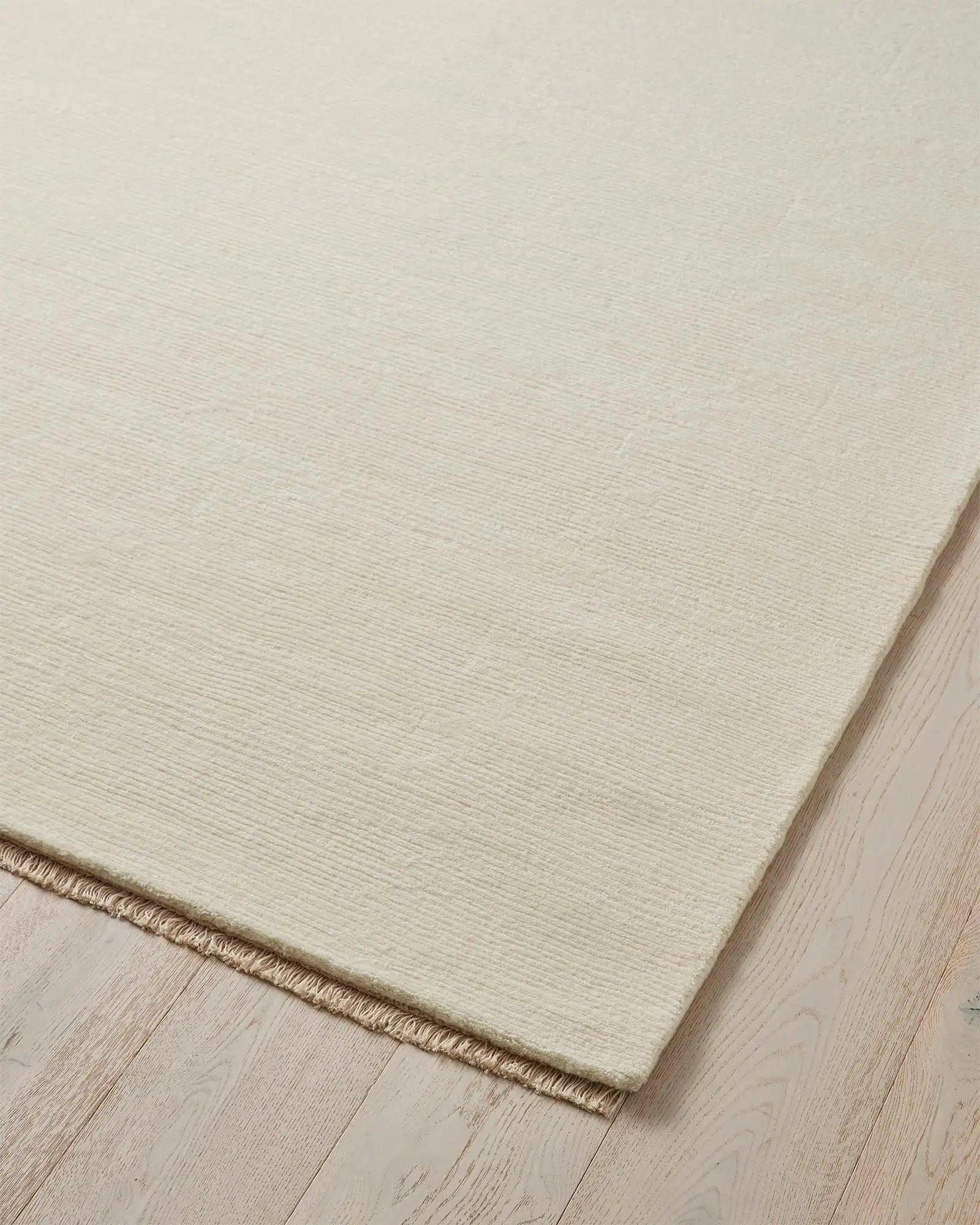 Alessandre Seasalt rug corner detail, hand-woven NZ wool in cool ivory with blanket stitch edge by Weave Home