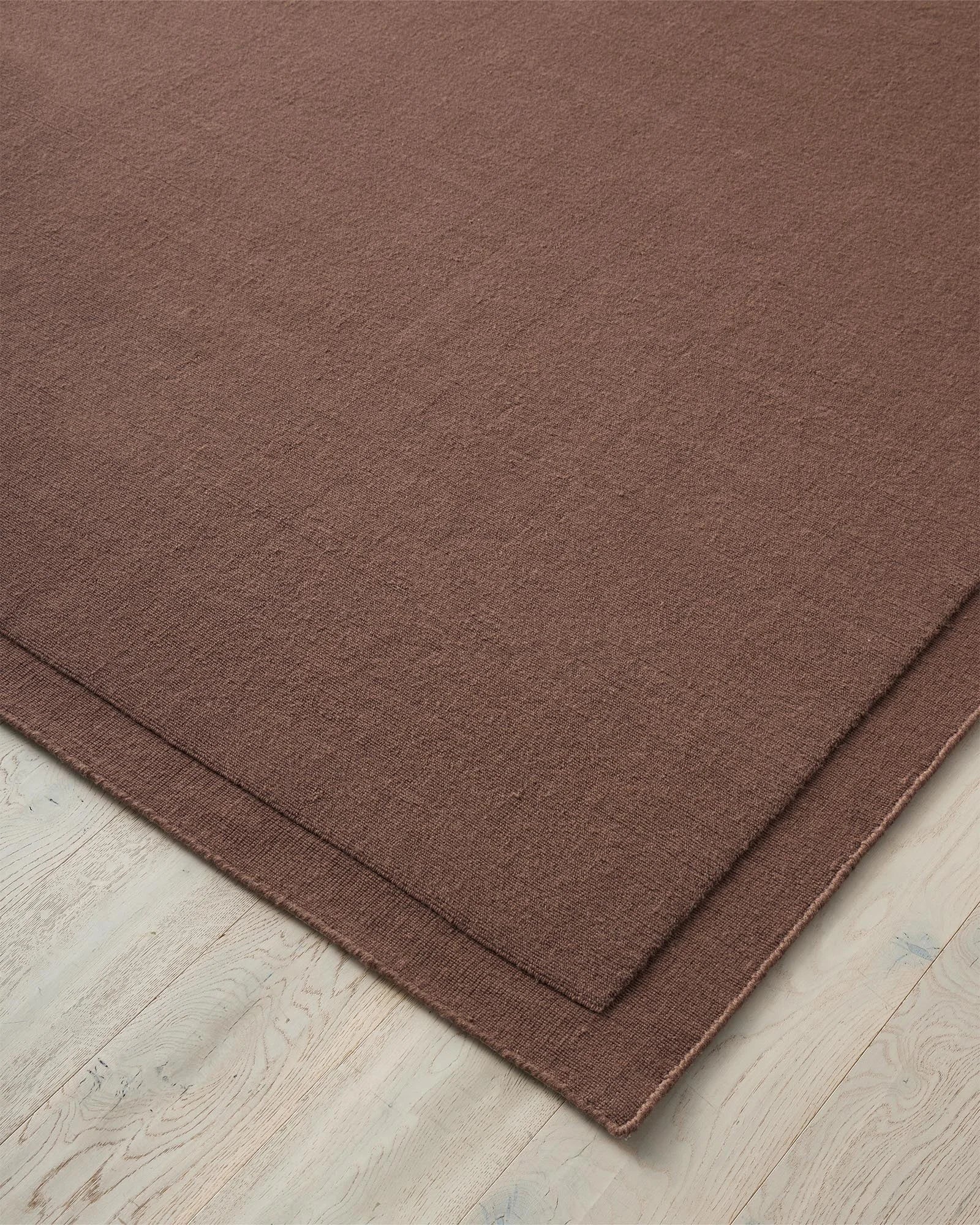 Cassio Mulberry rug in NZ wool, close-up of serged edge detail and tightly woven loop pile by Weave Home
