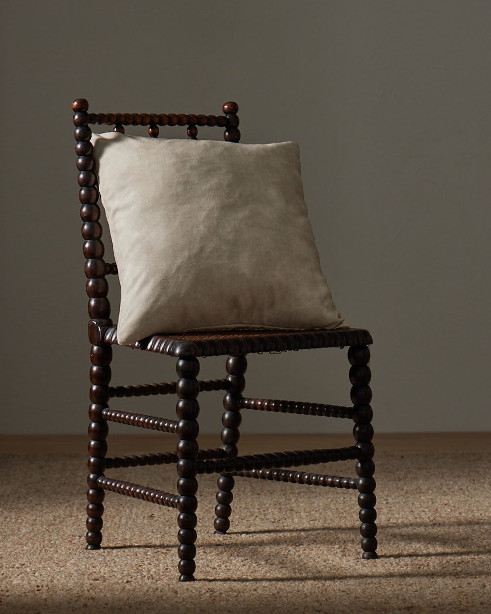 Ava Ecru 50x50 cushion in bone white polyester with velvet-like texture, styled on wooden chair by Weave Home