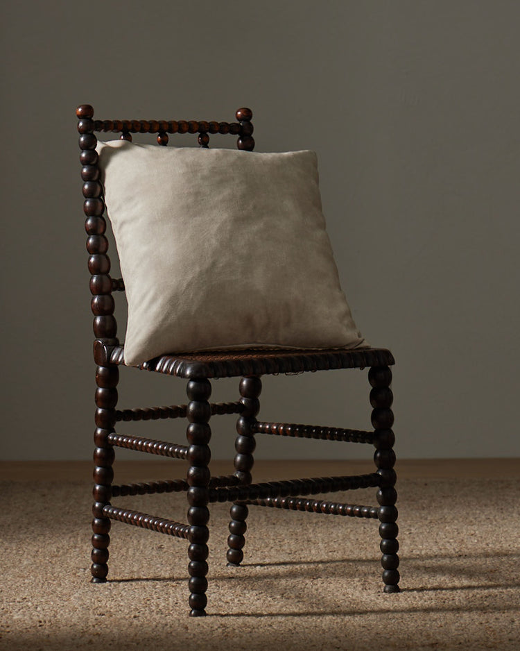 Ava Ecru 50x50 cushion in bone white polyester with velvet-like texture, styled on wooden chair by Weave Home