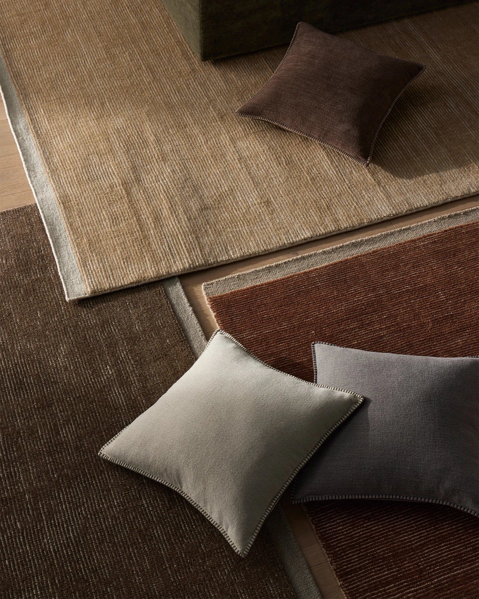 Warm earth-toned interior styled with textured wool rugs in sand and rust, layered with linen cushions in bone and bark for organic, neutral palette appeal