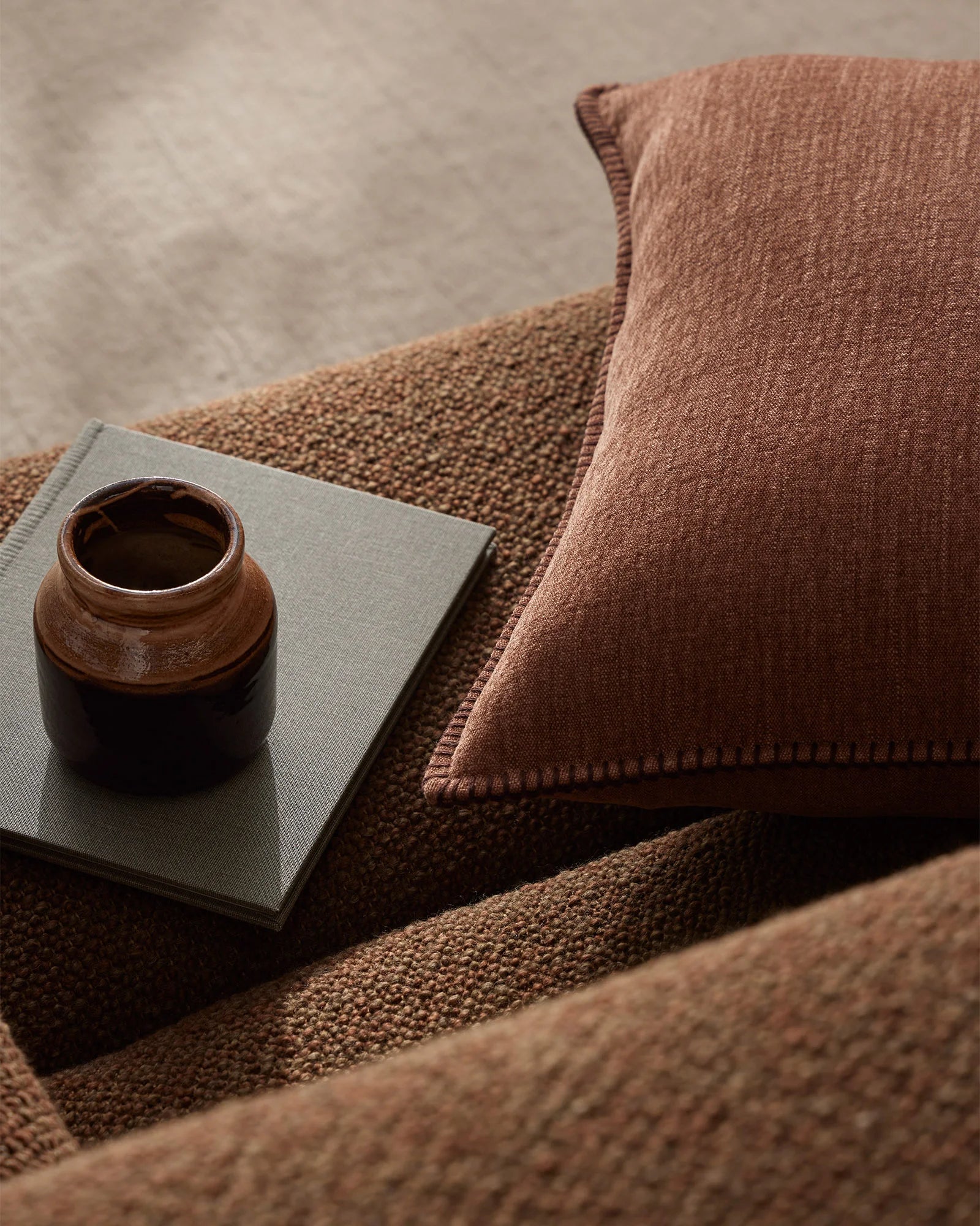 Earthy terracotta and neutral tones layer in a serene interior scene with Alba linen cushion, textured weave, and minimalist styling