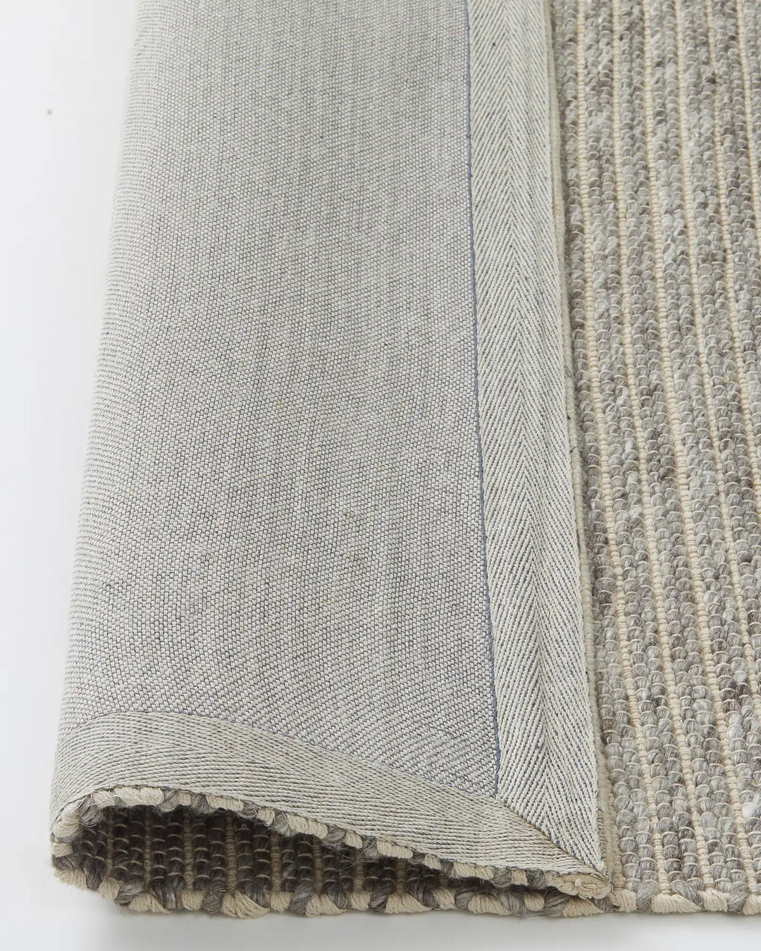 Andes Feather rug detail view showing ribbed wool-cotton weave texture with cotton backing and frayed edge by Weave Home