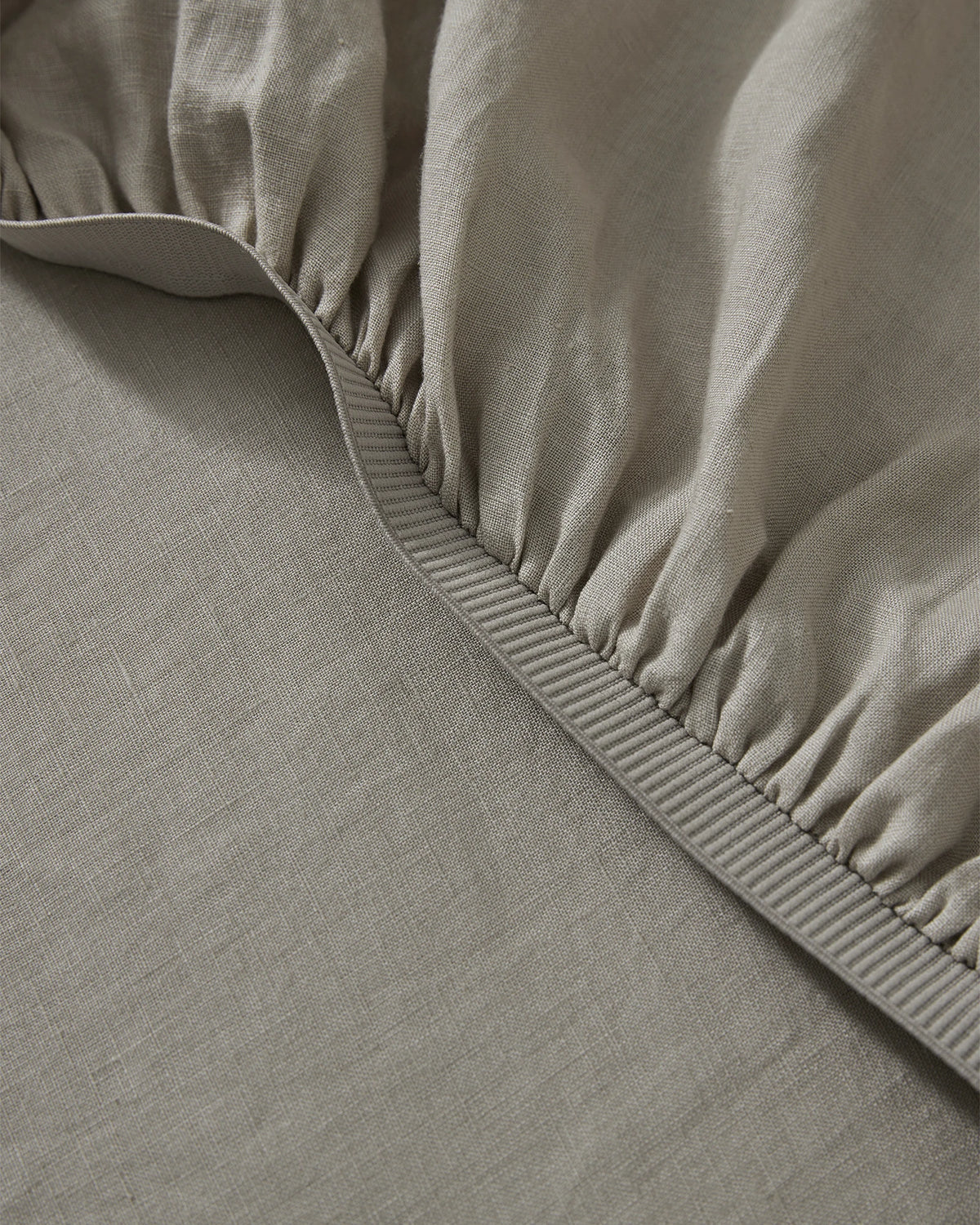 Ravello Fitted Sheet in Pebble, detail view of elastic-gathered corner with thick binding seam, European linen by Weave Home