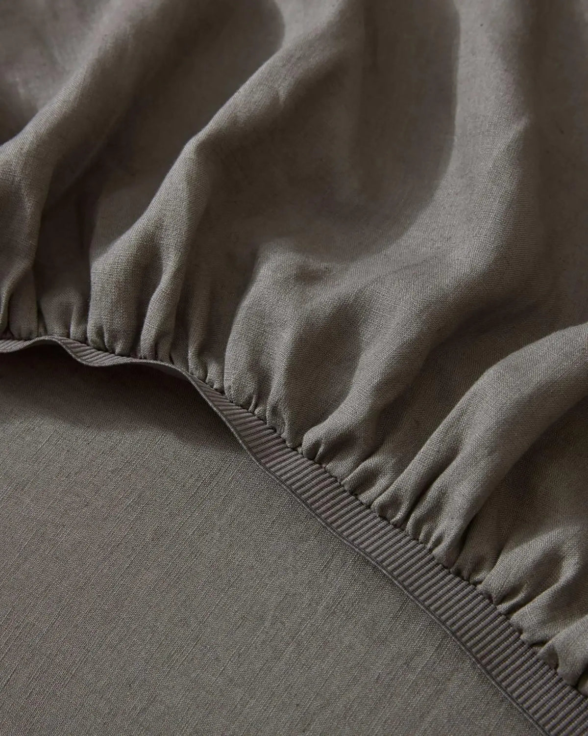 Ravello Fitted Sheet in Charcoal, close-up of elastic edge detail and soft European linen weave by Weave Home