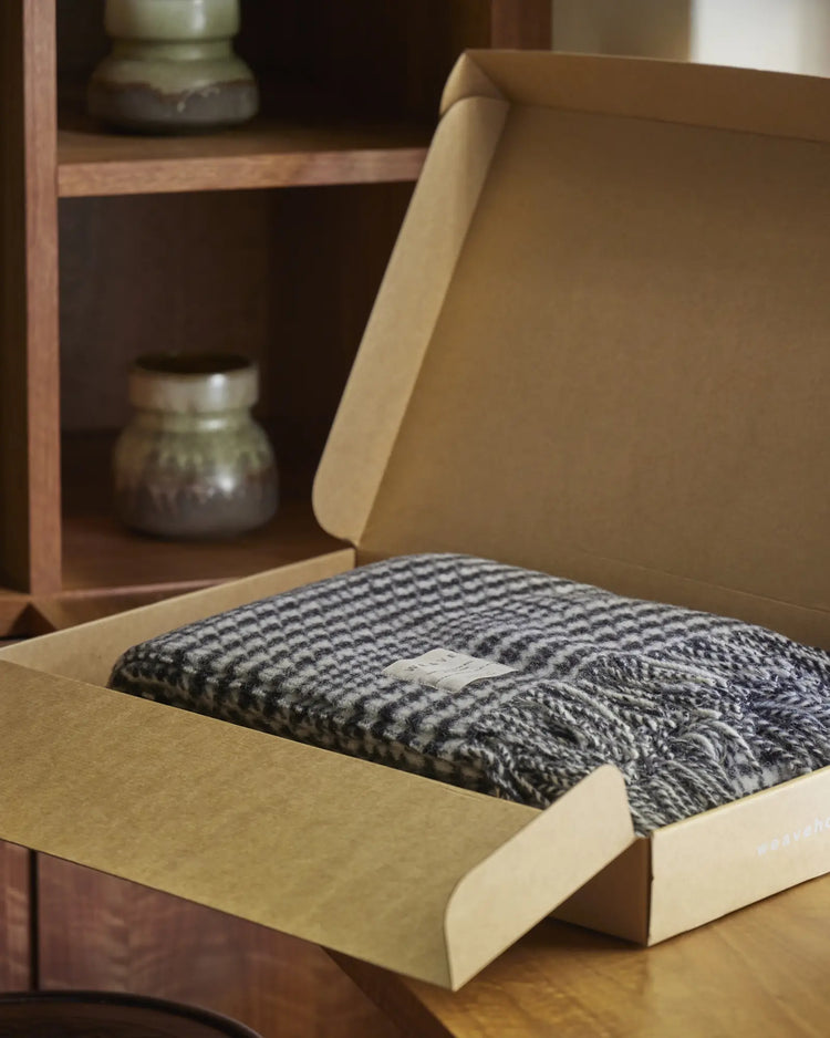 Helmsdale Midnight throw in black and white houndstooth check, NZ wool with fringe edge, displayed in kraft packaging by Weave Home