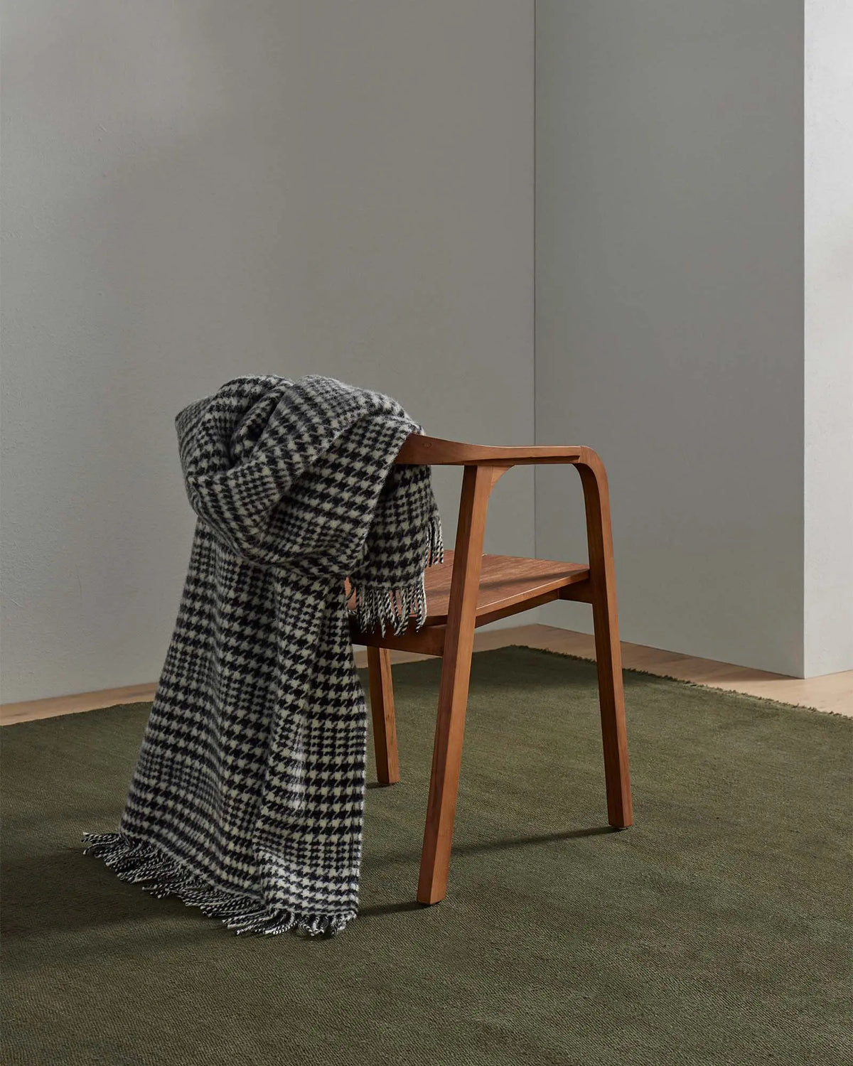 Helmsdale Midnight throw in black and white houndstooth check with fringe edge, draped over wooden chair by Weave Home
