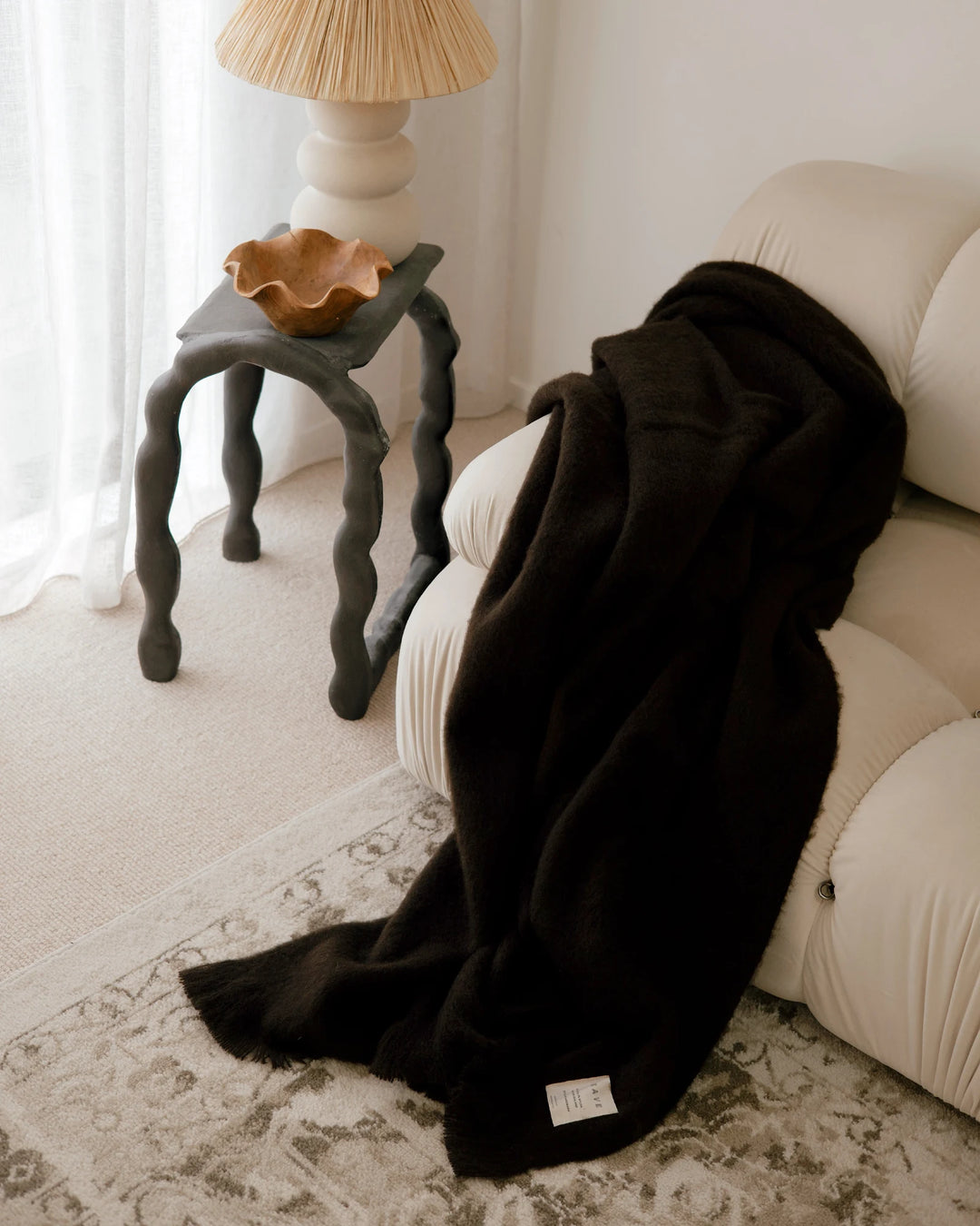 Hyde Cocoa wool blend throw in rich charcoal, draped over cream chair with plush brushed finish detail by Weave Home
