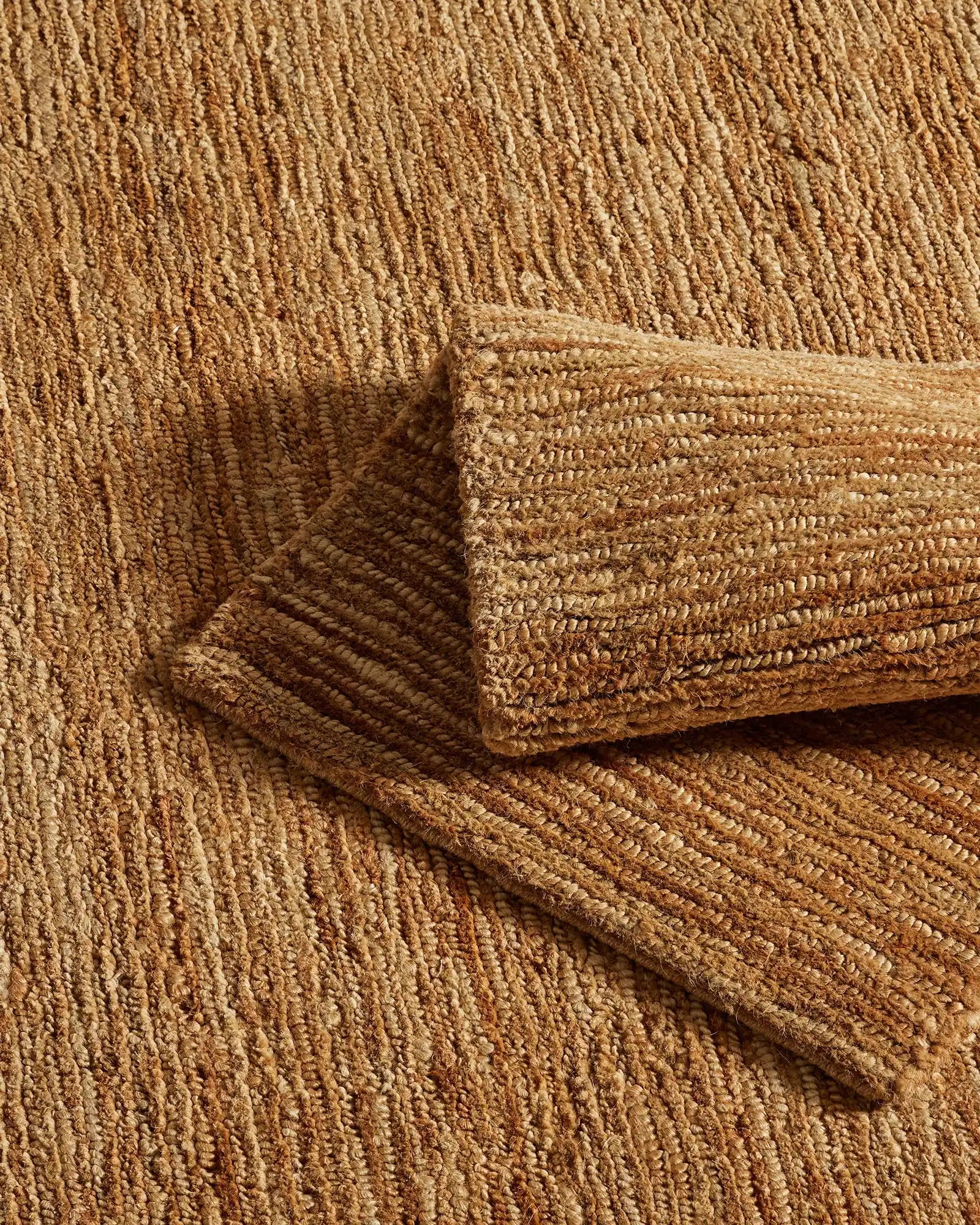 Jute rug layered with textured throw in warm natural tones, showcasing woven texture detail and earthy neutral palette