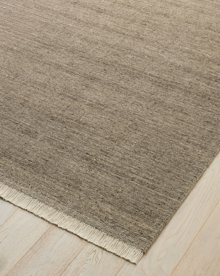 Anton Ash hand-woven wool rug detail, grey-neutral with warm brown undertones and cream speckles, off-white cotton fringe by Weave Home