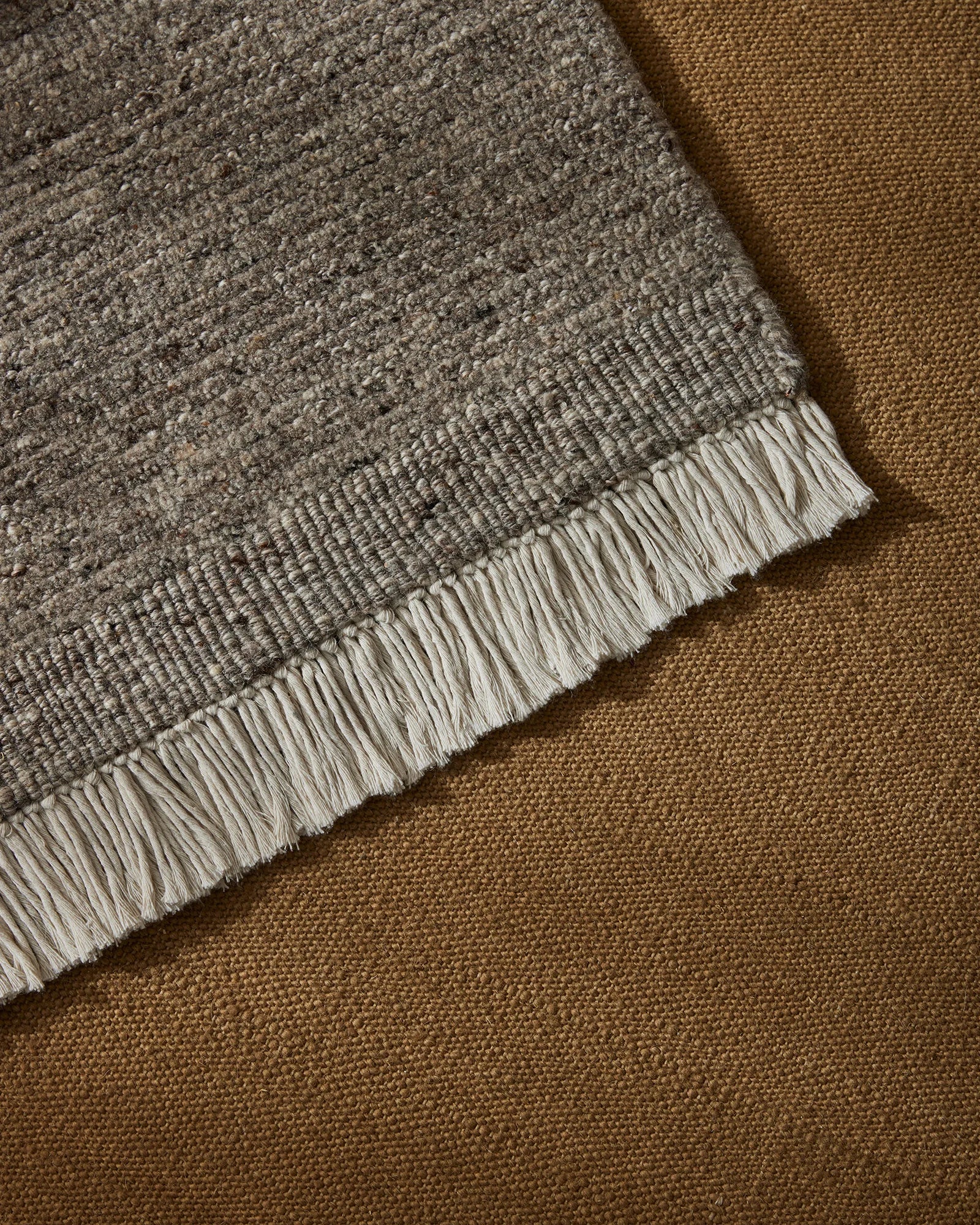Anton Ash wool rug detail showing cut and loop pile texture with off-white cotton fringe border by Weave Home