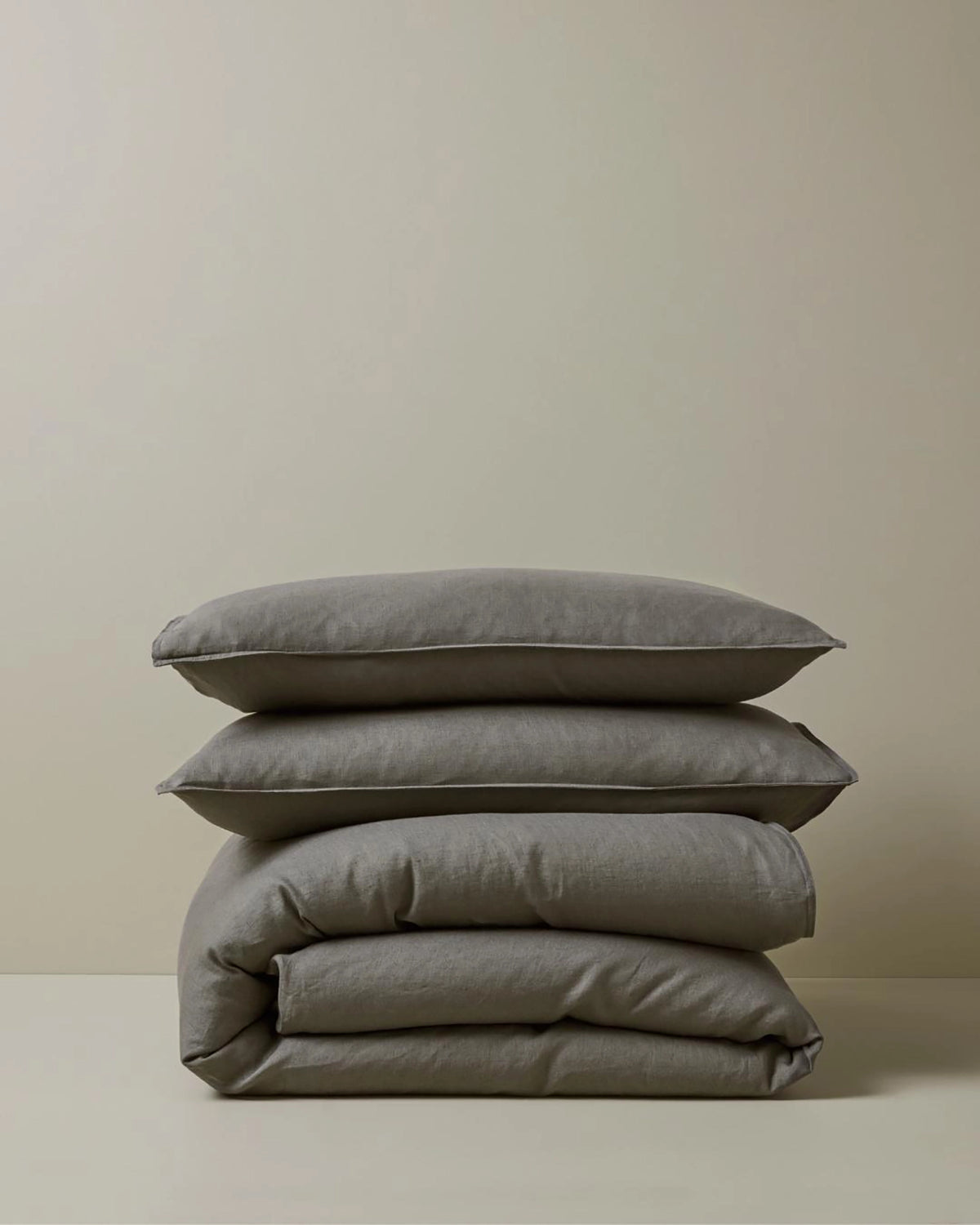 Ravello Pillowcase Set in charcoal, stacked with European linen pillows featuring top-stitched flanged edges by Weave Home