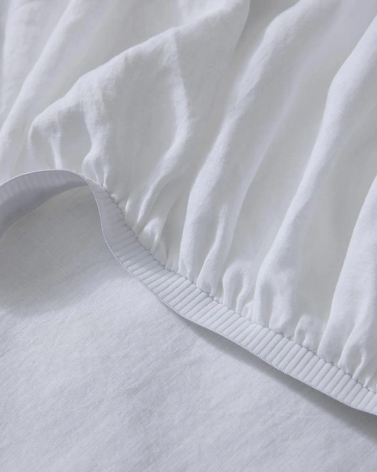 Ravello Fitted Sheet in white European linen, detail of elastic edge with blanket stitch seam by Weave Home