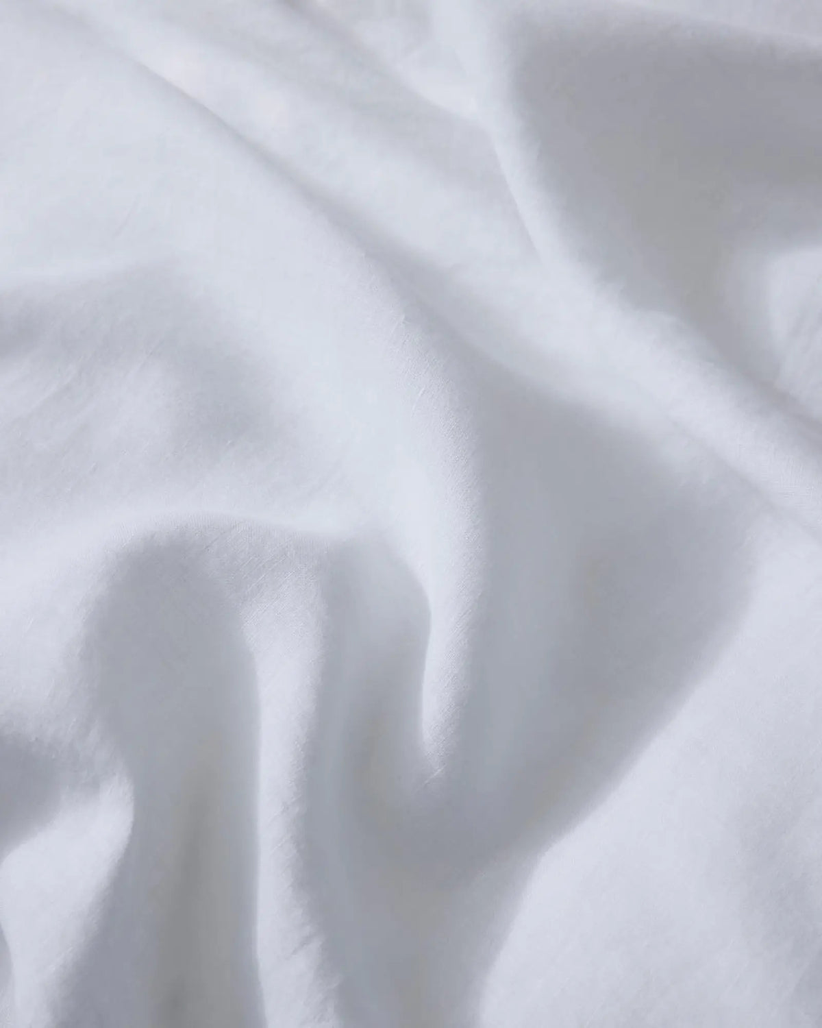 Close-up of crisp white linen bedding with soft folds and natural texture, highlighting the breathable European linen weave and minimalist aesthetic of Ravello sheets