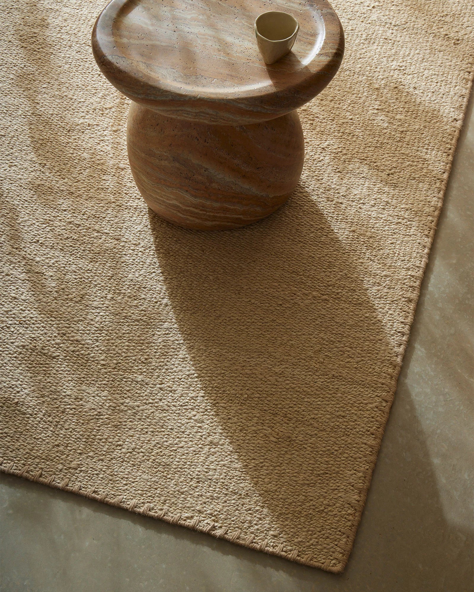 Natural cream textured rug styled with wooden side table and brass vessel, earthy minimalist aesthetic with warm neutral palette
