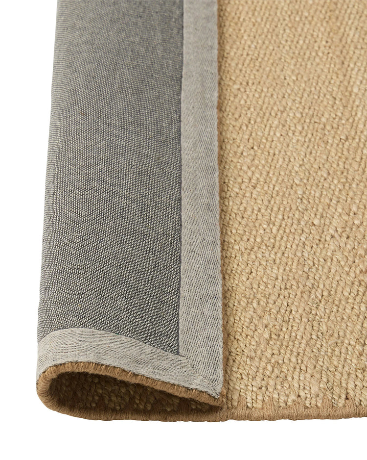 Monroe Oat rug detail view showing woven polyester texture with blanket stitch edge and natural jute-look finish by Weave Home