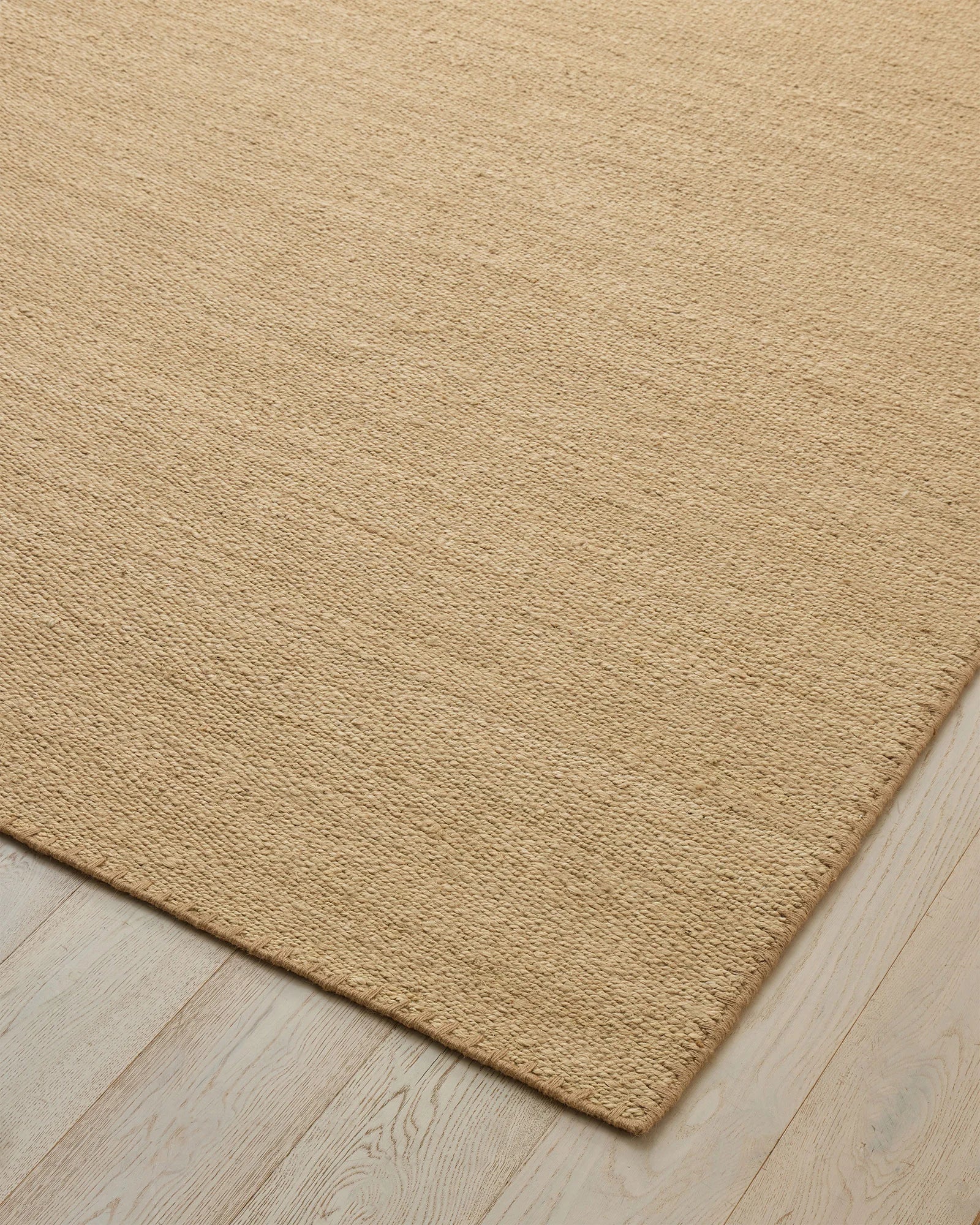 Monroe Oat high-traffic rug in warm sand neutral, showing woven polyester texture with blanket stitch border detail by Weave Home