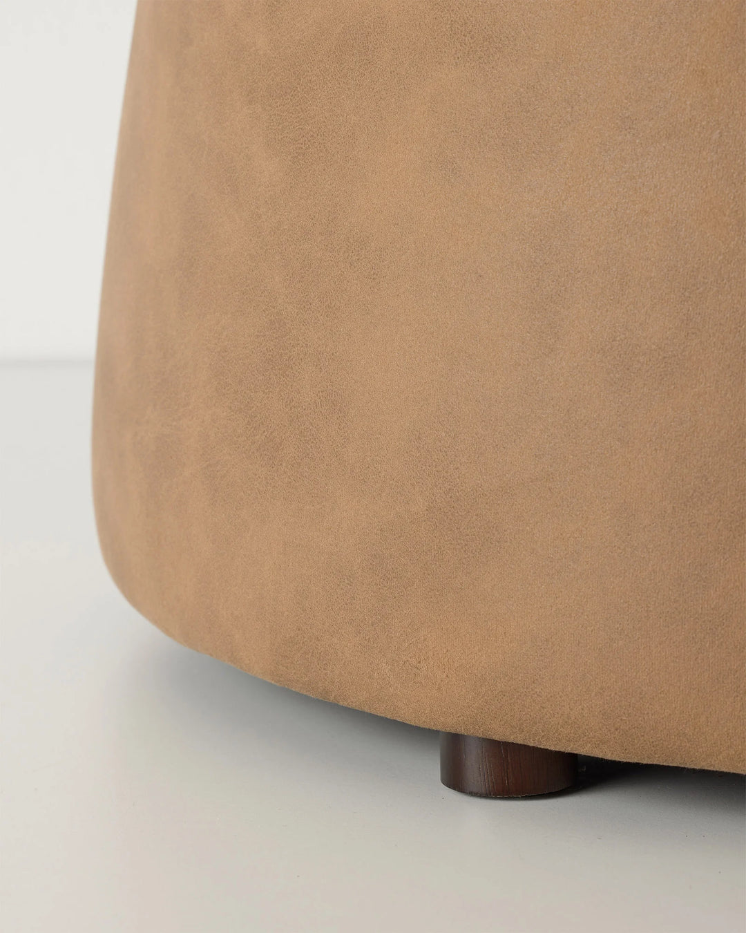 Landro Toffee ottoman, close-up of warm brown polyester upholstery with subtle leather grain texture and wooden leg detail by Weave Home