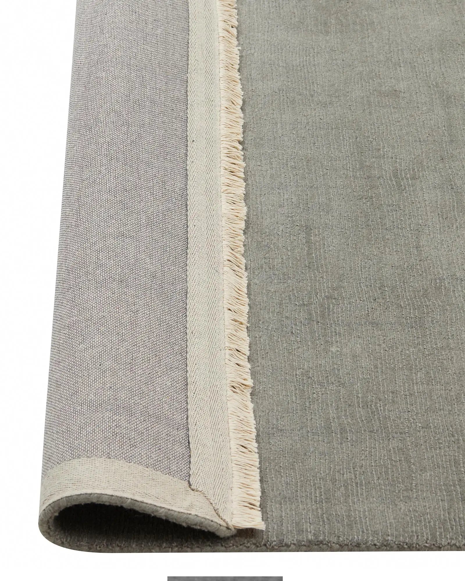 Alessandre Mineral rug detail view showing hand-woven NZ wool with natural fringe edge and cotton backing by Weave Home