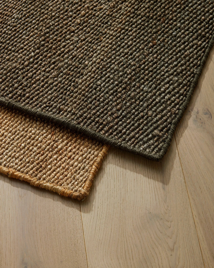 Layered jute door mats in graphite and wheat tones on light timber flooring, showcasing natural fibre texture and earthy neutral palette for entryway styling