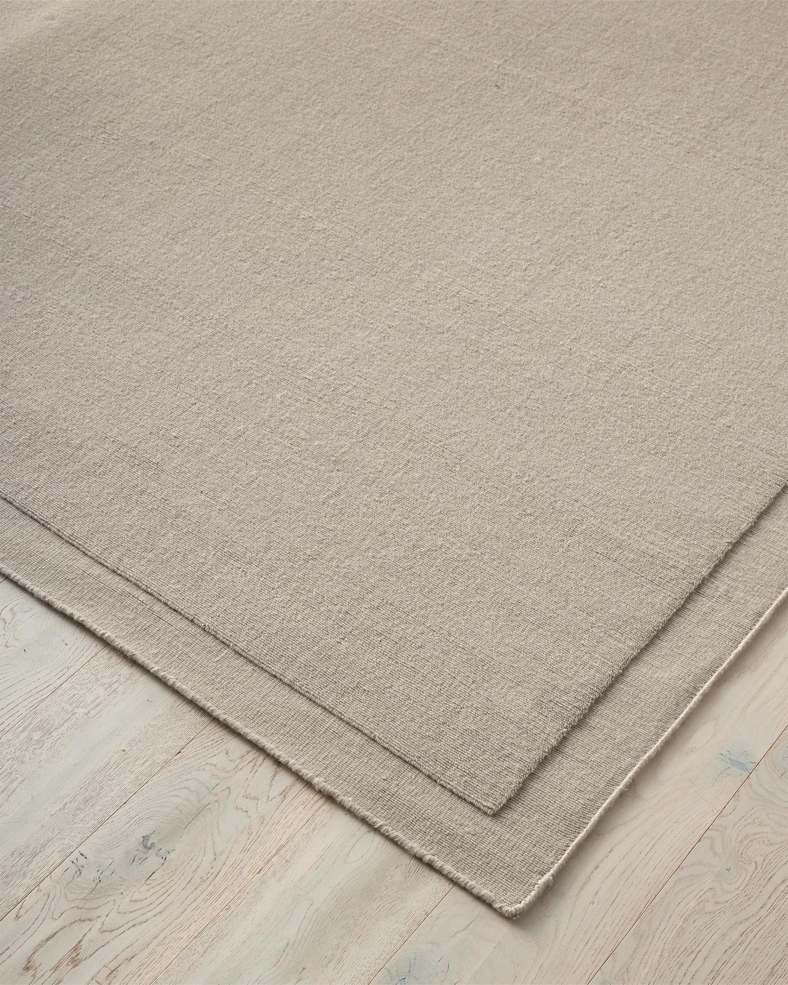 Cassio Fog 3x4m wool rug detail view, showing ecru tightly woven loop pile with hand-stitched serged edge by Weave Home