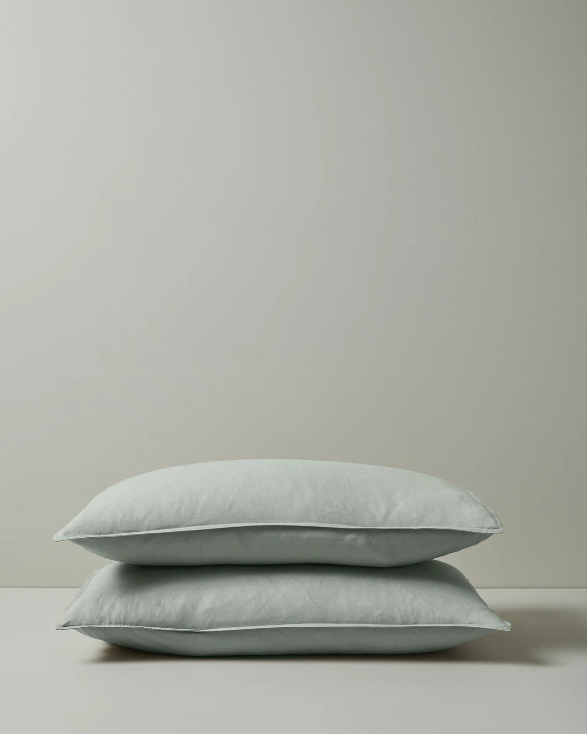 Ravello Pillowcase Set in sage, pair stacked showing soft European linen with top-stitched flanged edge by Weave Home