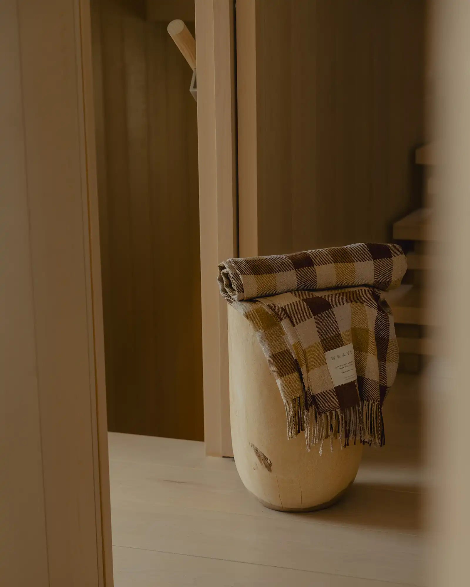 Caldwell Autumn wool throw in taupe, cocoa and ochre plaid, draped over wooden rail with fringe trim by Weave Home
