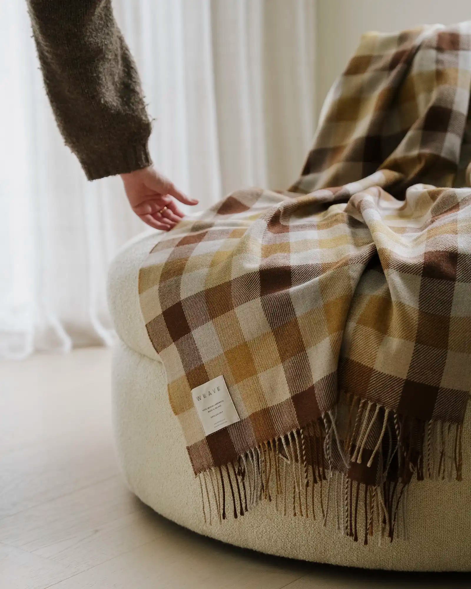 Caldwell Autumn wool throw in taupe, cocoa and ochre plaid with fringed edges, draped on sofa by Weave Home