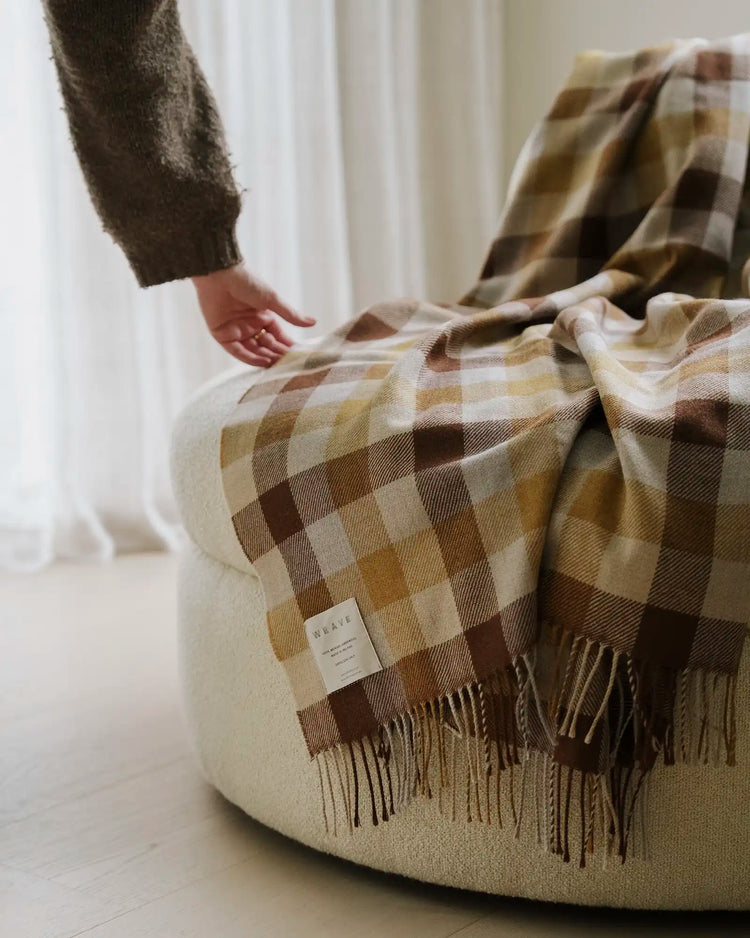 Caldwell Autumn wool throw in taupe, cocoa and ochre plaid with fringed edges, draped on sofa by Weave Home