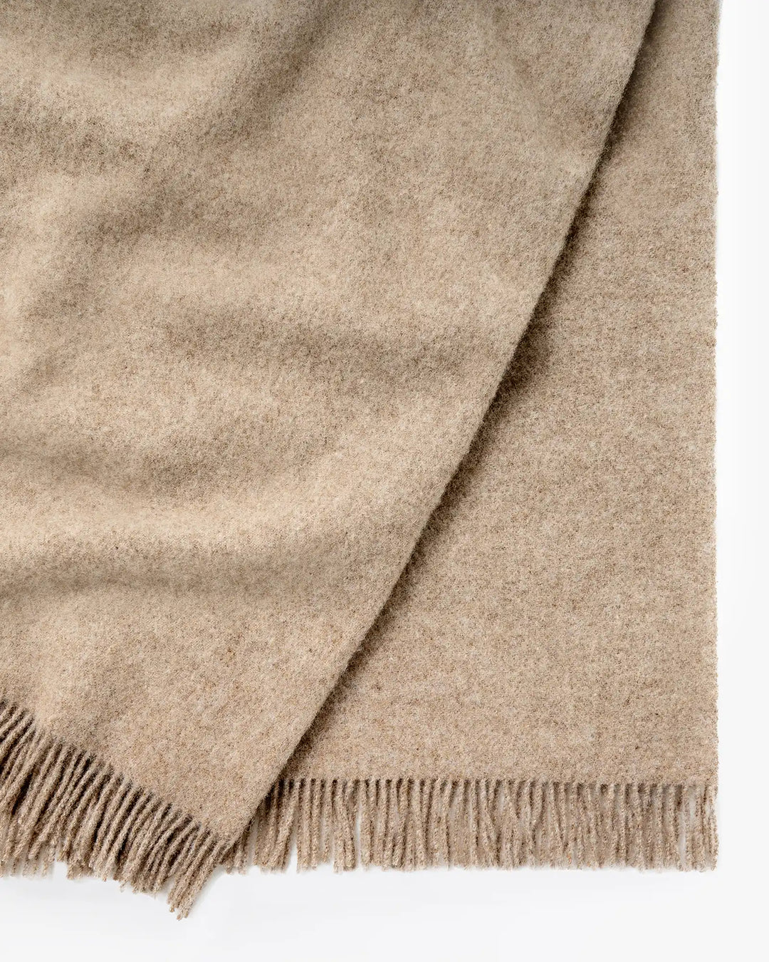 Nevis Oak lambswool throw in soft brown, close-up detail showing tassel fringe border and textured weave by Weave Home