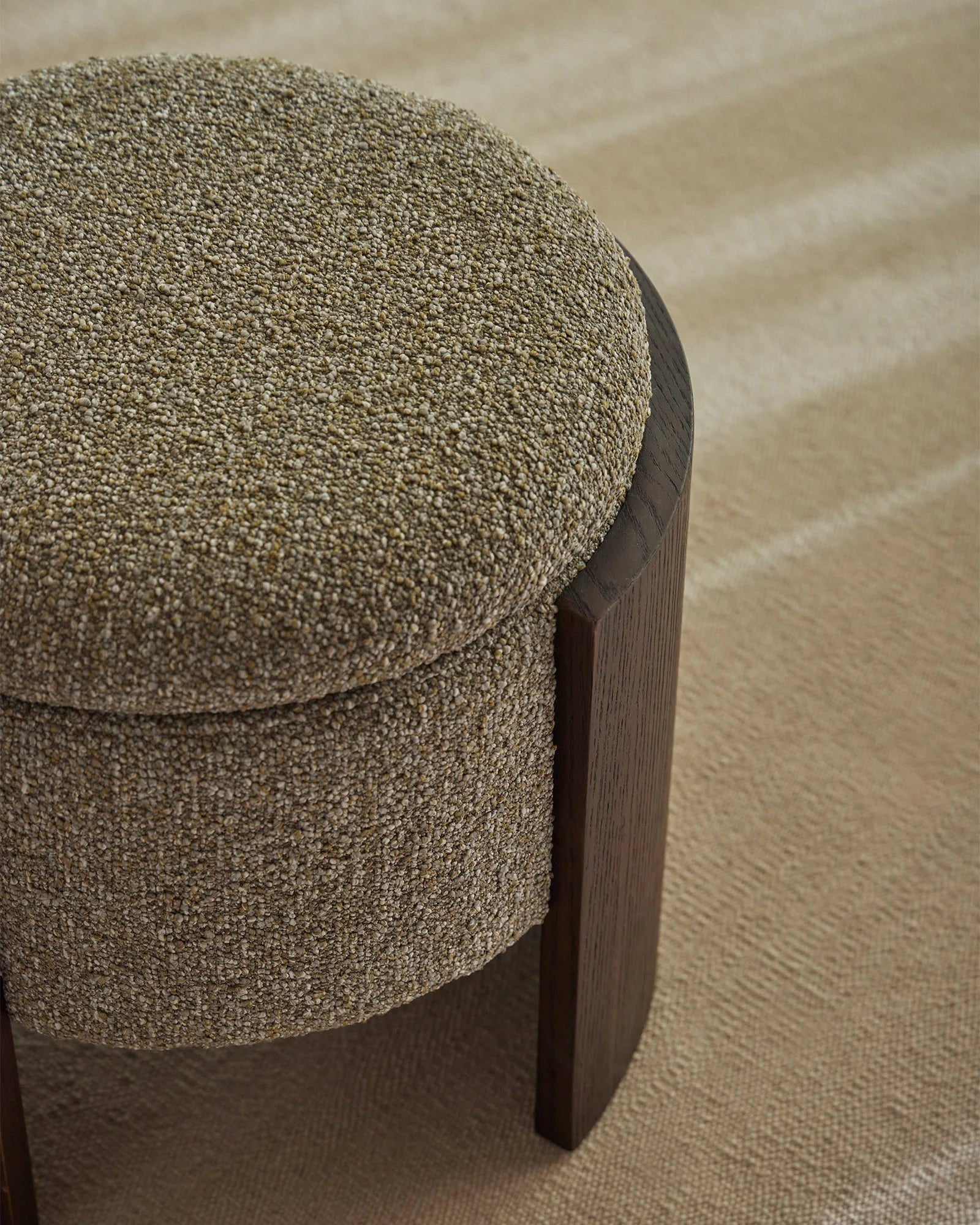 Sage green boucle ottoman with dark timber base on neutral textured flooring, modern minimalist home décor styling with warm earthy tones