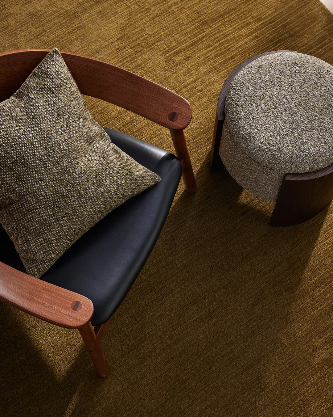 Mid-century chairs with textured linen cushions on golden moss rug, natural materials styled in warm earthy tones with wood frames and subtle Scandinavian aesthetic
