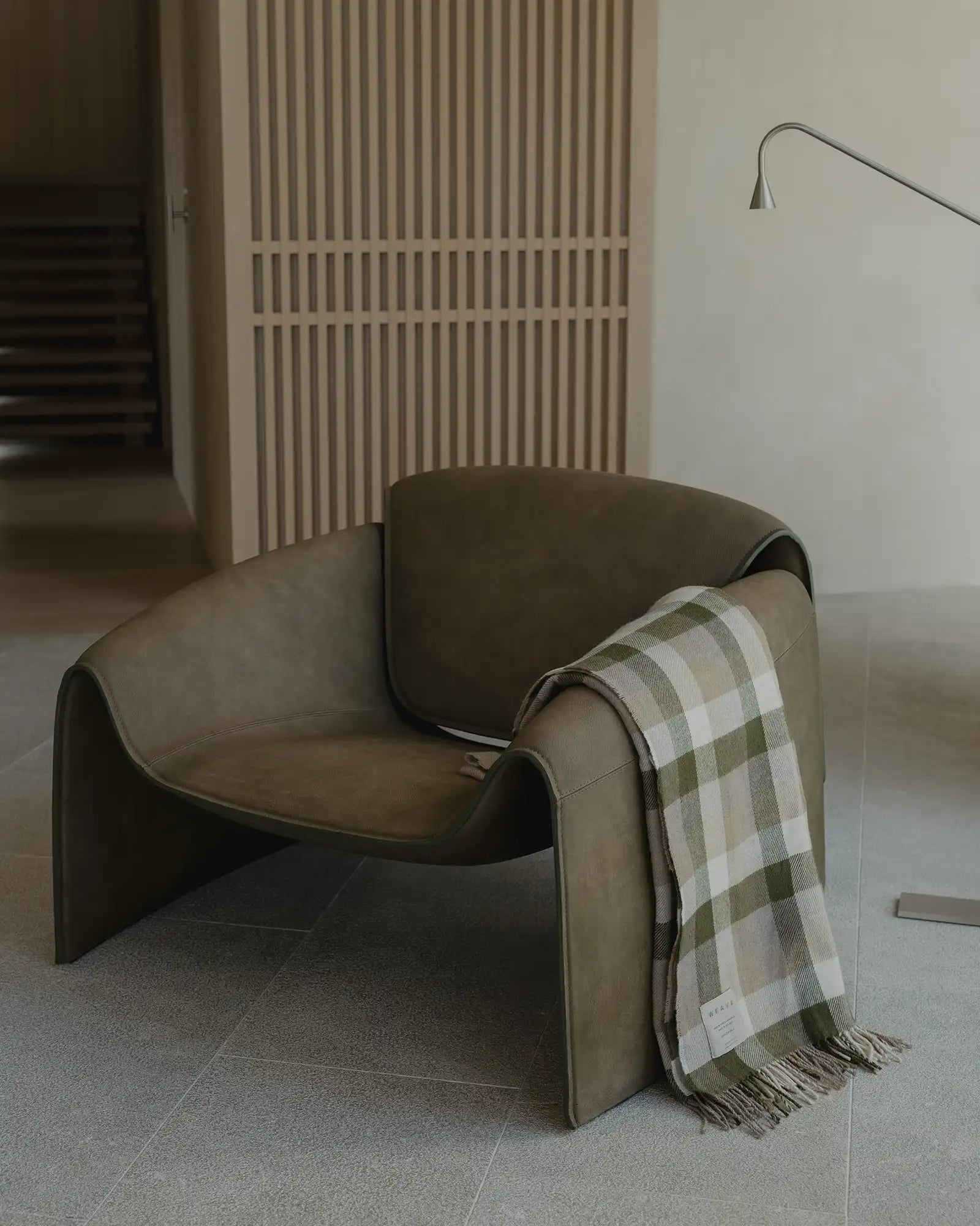 Caldwell Landscape throw in taupe, moss green and white plaid, draped over chair arm, woven merino lambswool with fringe edge by Weave Home