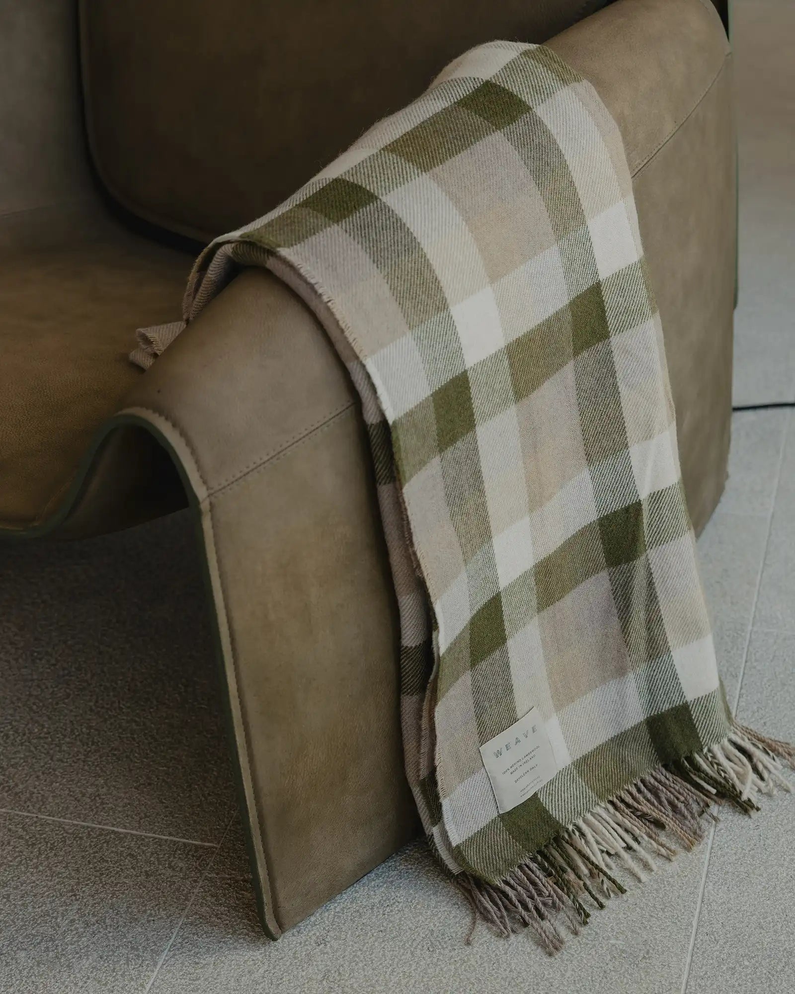 Caldwell Landscape wool throw in taupe, moss and cream check with fringed edge detail, draped over sofa arm by Weave Home