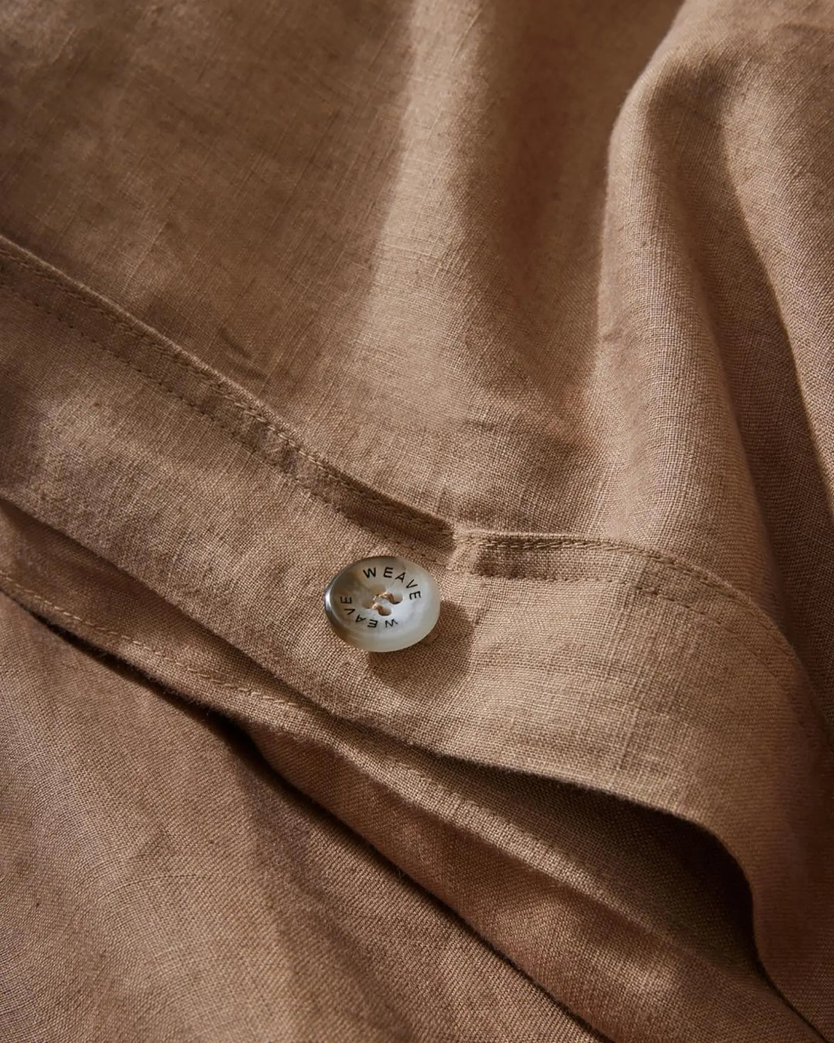 Ravello Quilt Cover in Biscuit, close-up detail of branded button closure on European linen by Weave Home