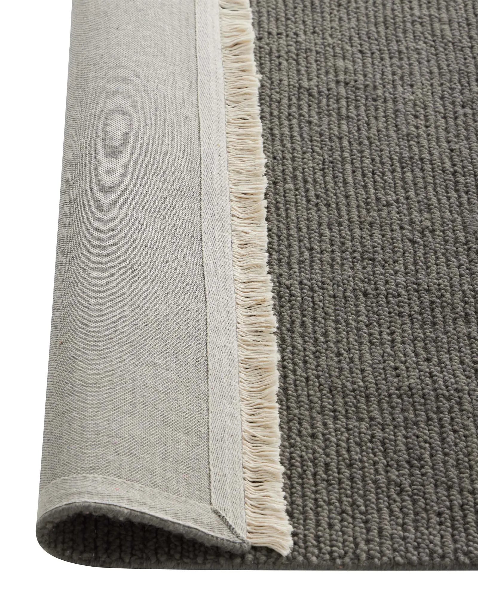 Fabien Echo textured wool rug in medium grey, showing chunky ribbed weave and cream fringe border detail, by Weave Home